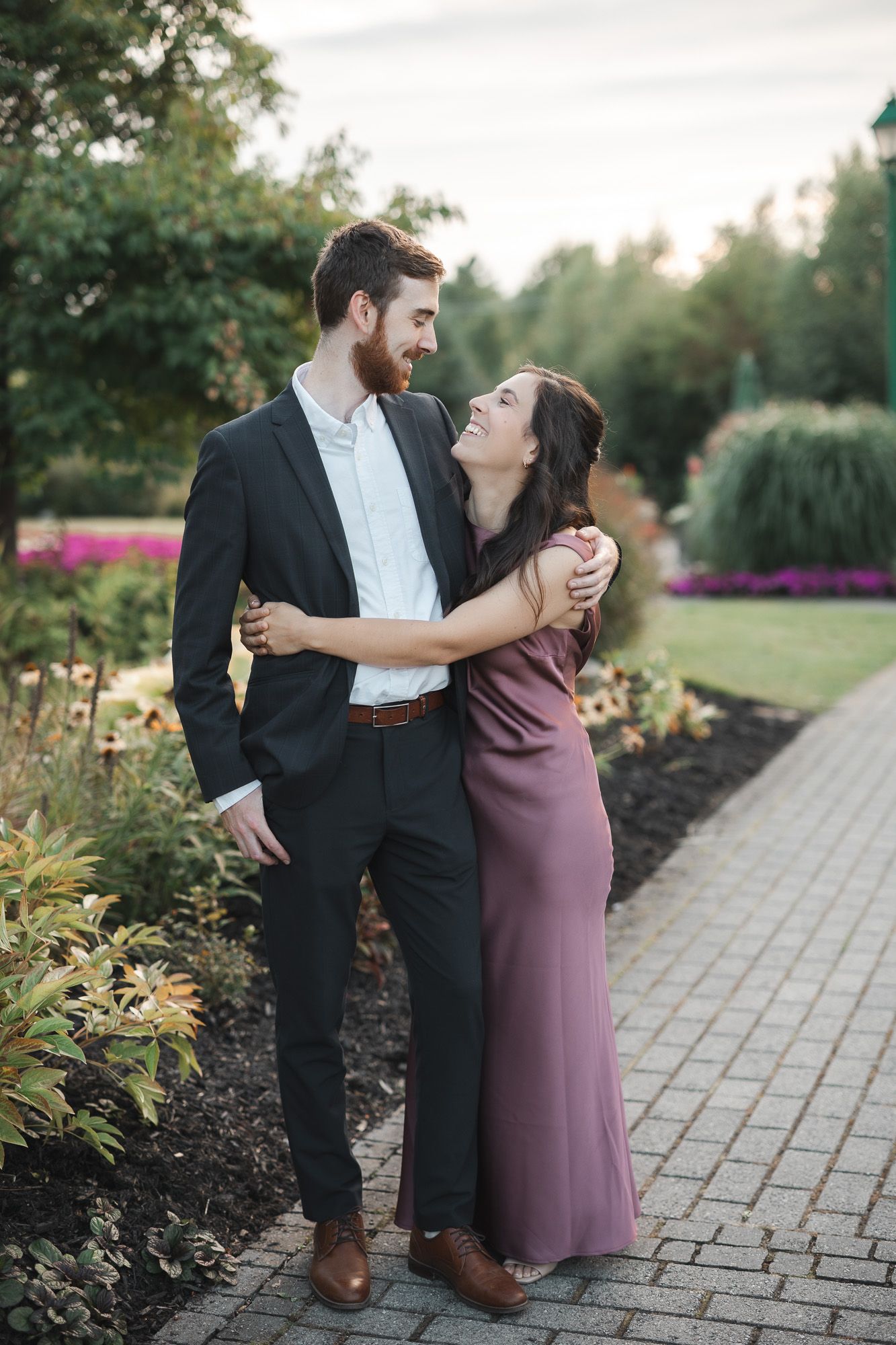 Couple partageant un moment romantique sur un sentier de jardin entouré de fleurs colorées et d’aménagement paysager, en Estrie