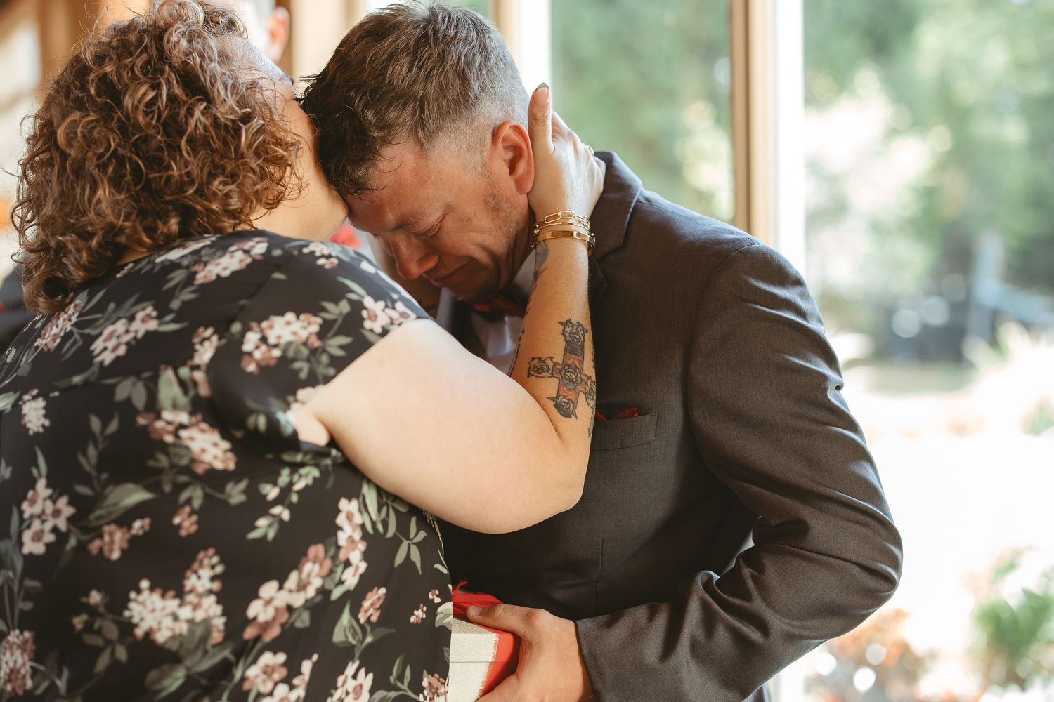 A romantic couple embraces and dances together in a sunlit room with natural window light.