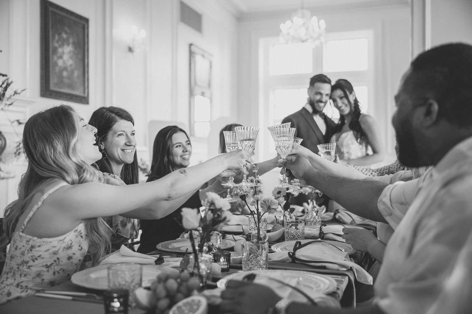 A group of people celebrating and laughing together at a social gathering in a bright indoor space.