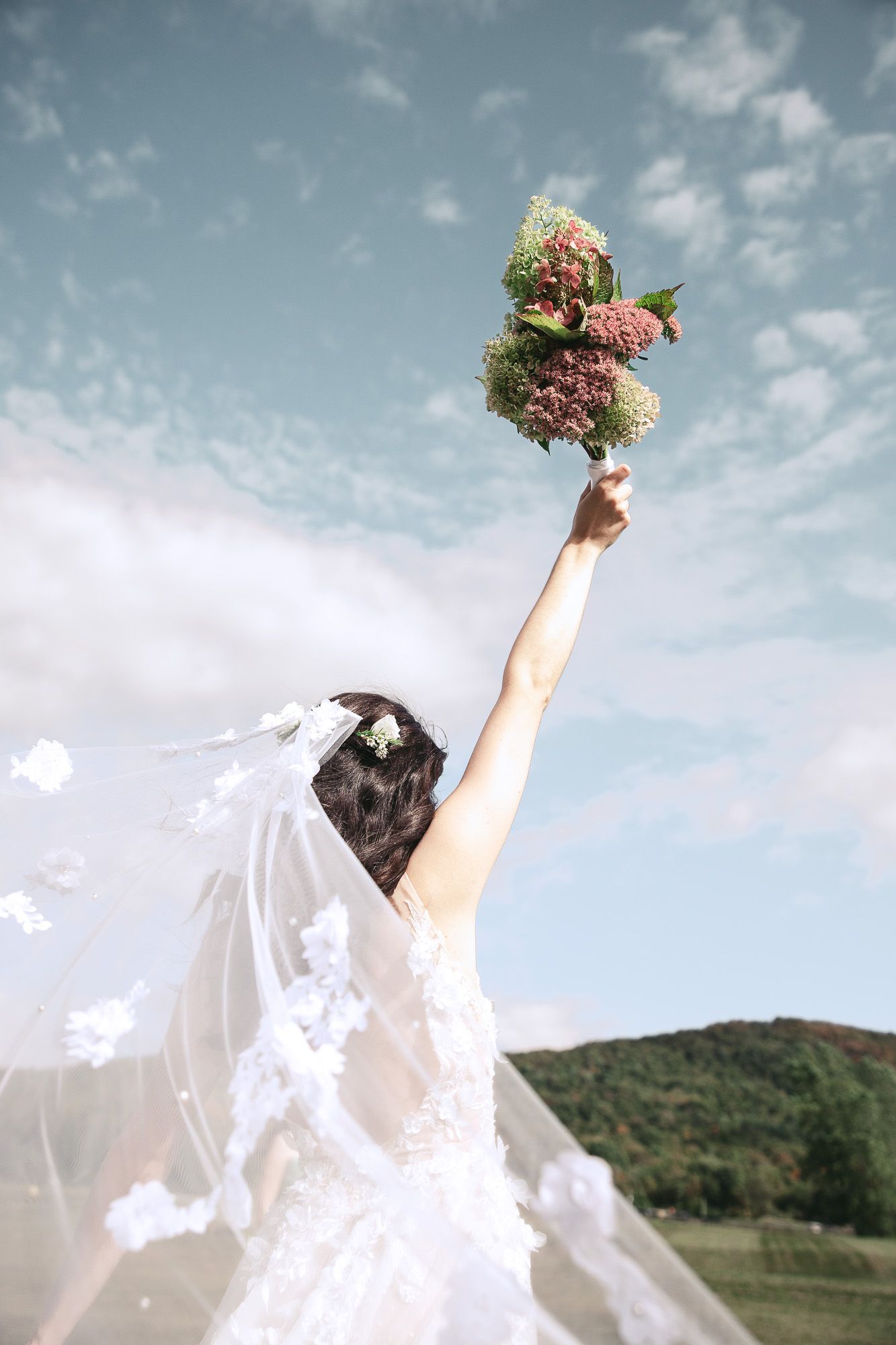 Lancer de bouquet de mariage sur fond de ciel nuageux et montagnes, en Estrie