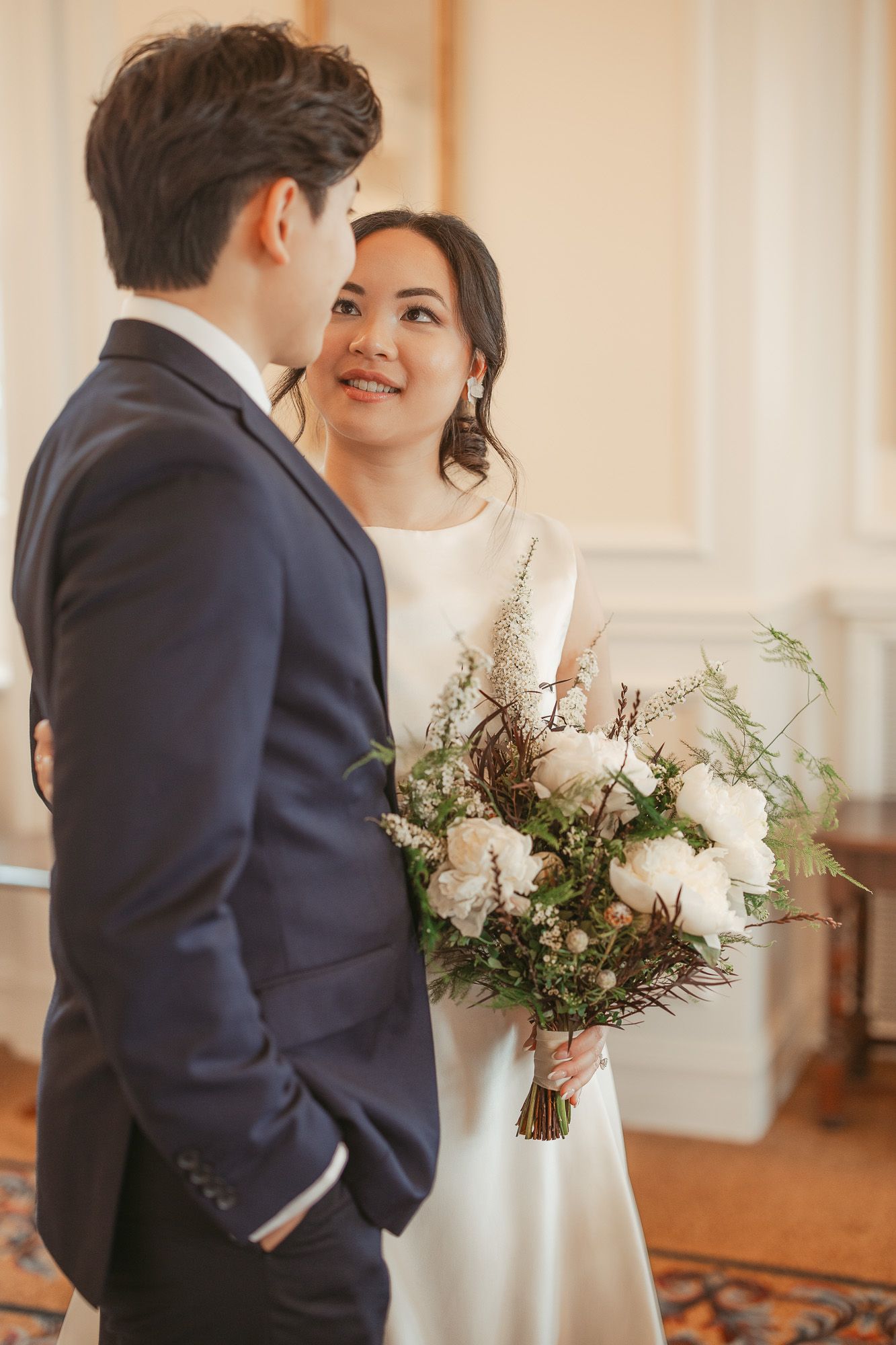 Moment romantique de mariage capté dans une salle de bal élégante avec lustres en cristal et compositions florales blanches