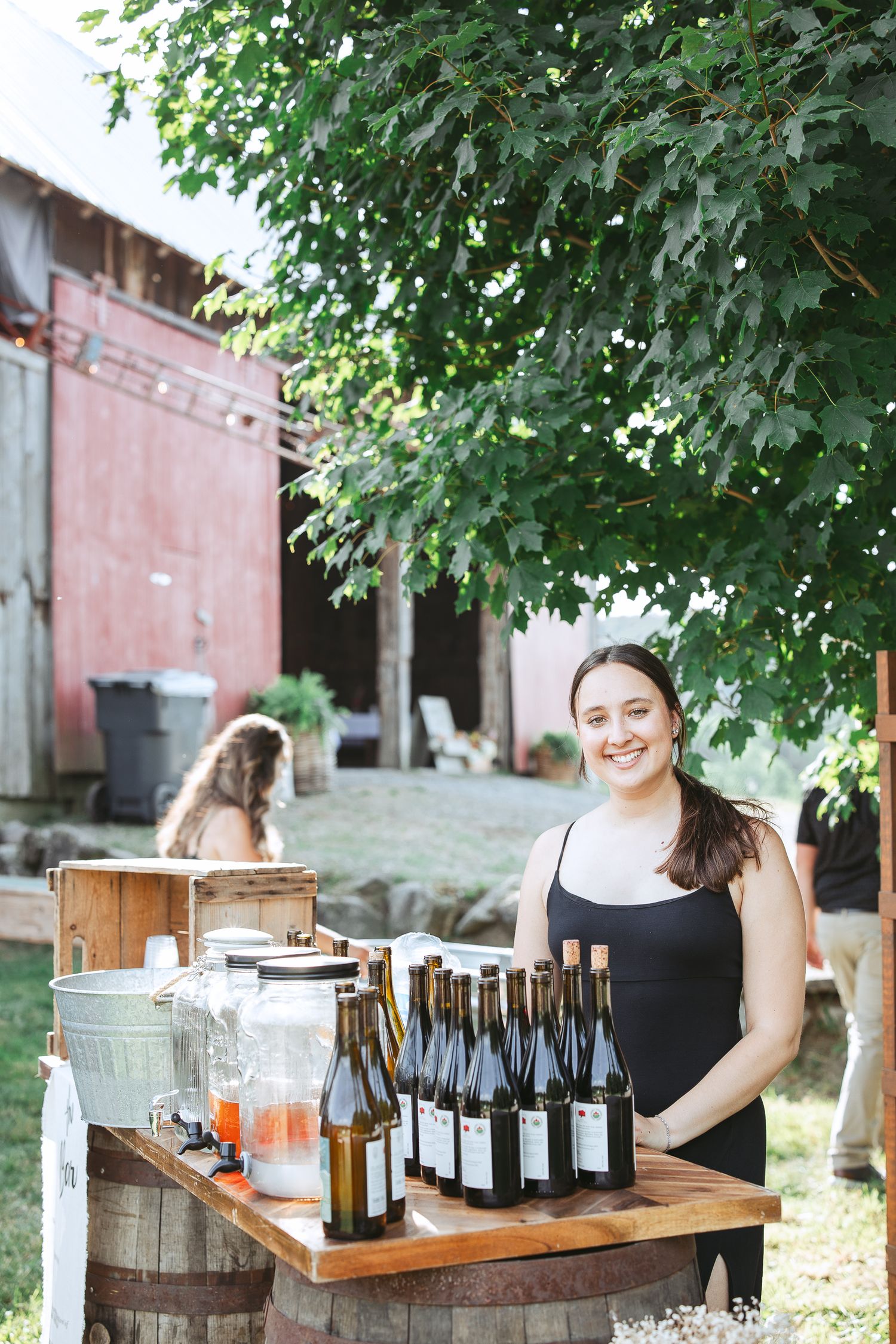 Dégustation de vin extérieure rustique avec bouteilles présentées sur un baril en bois sous des arbres feuillus