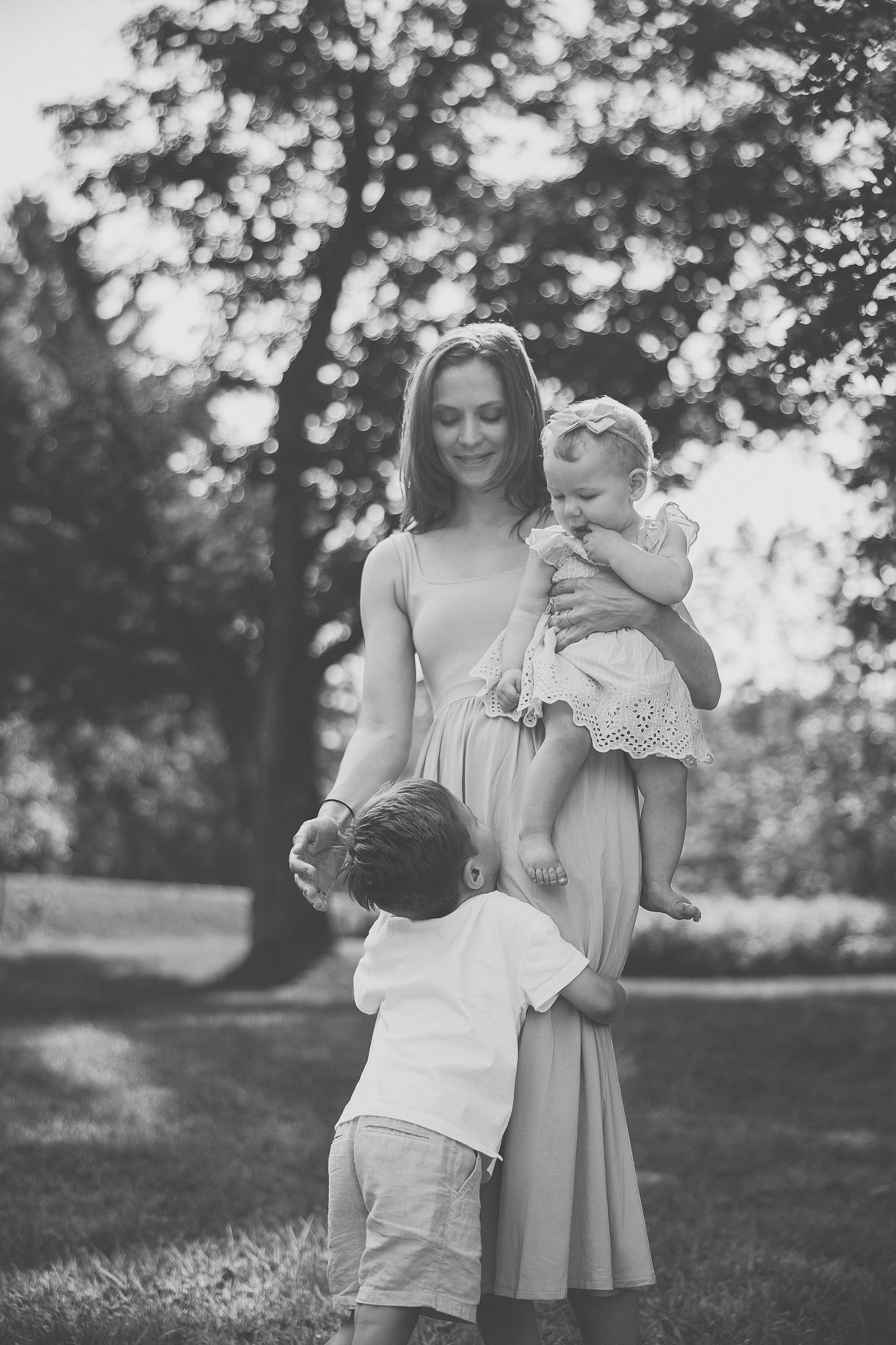 Parent et enfant photographiés en noir et blanc dans un parc, partageant des instants tendres pour valorisation de lien familial et émotion