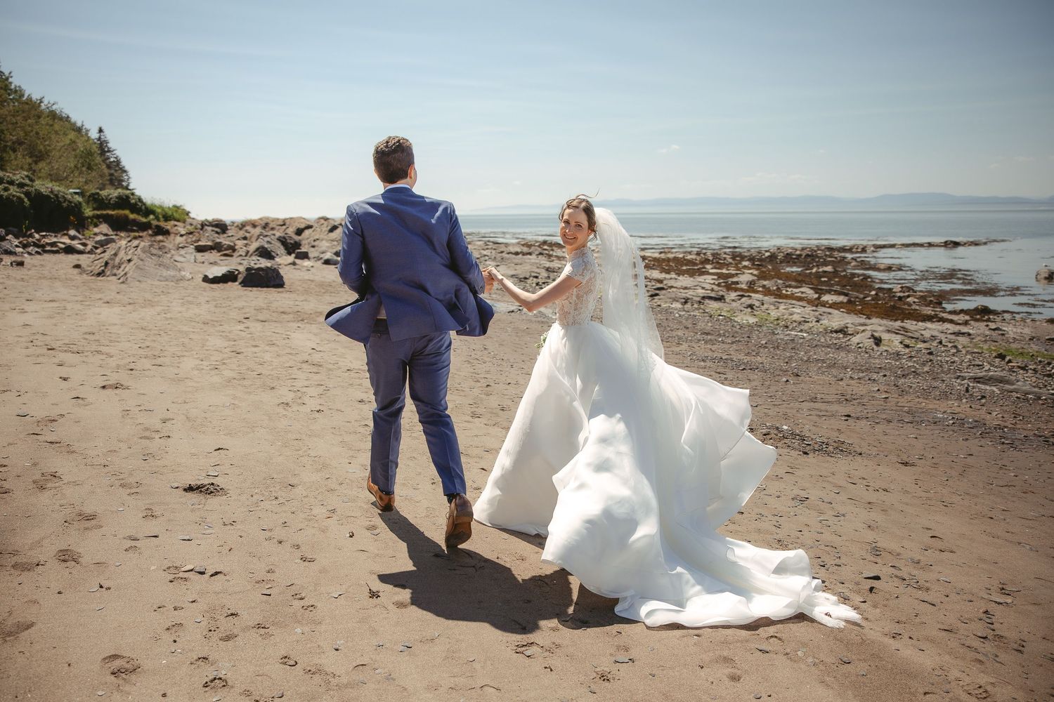 Couple de mariés partageant un moment intime au coucher du soleil, le long d’une plage au décor naturel et romantique.
