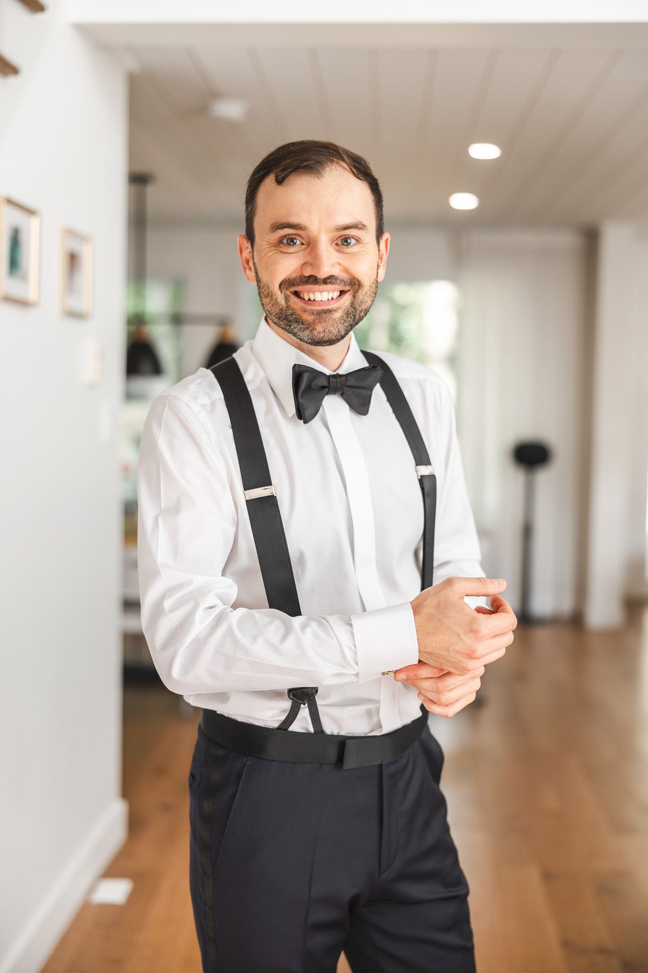 Futur marié en tenue formelle avec nœud papillon et bretelles, dans un intérieur élégant