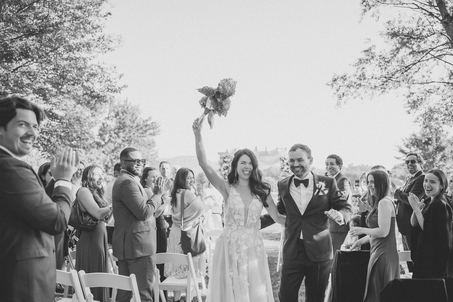 Célébration joyeuse lors d’une cérémonie de mariage en plein air, invités applaudissant depuis des chaises blanches, en Estrie