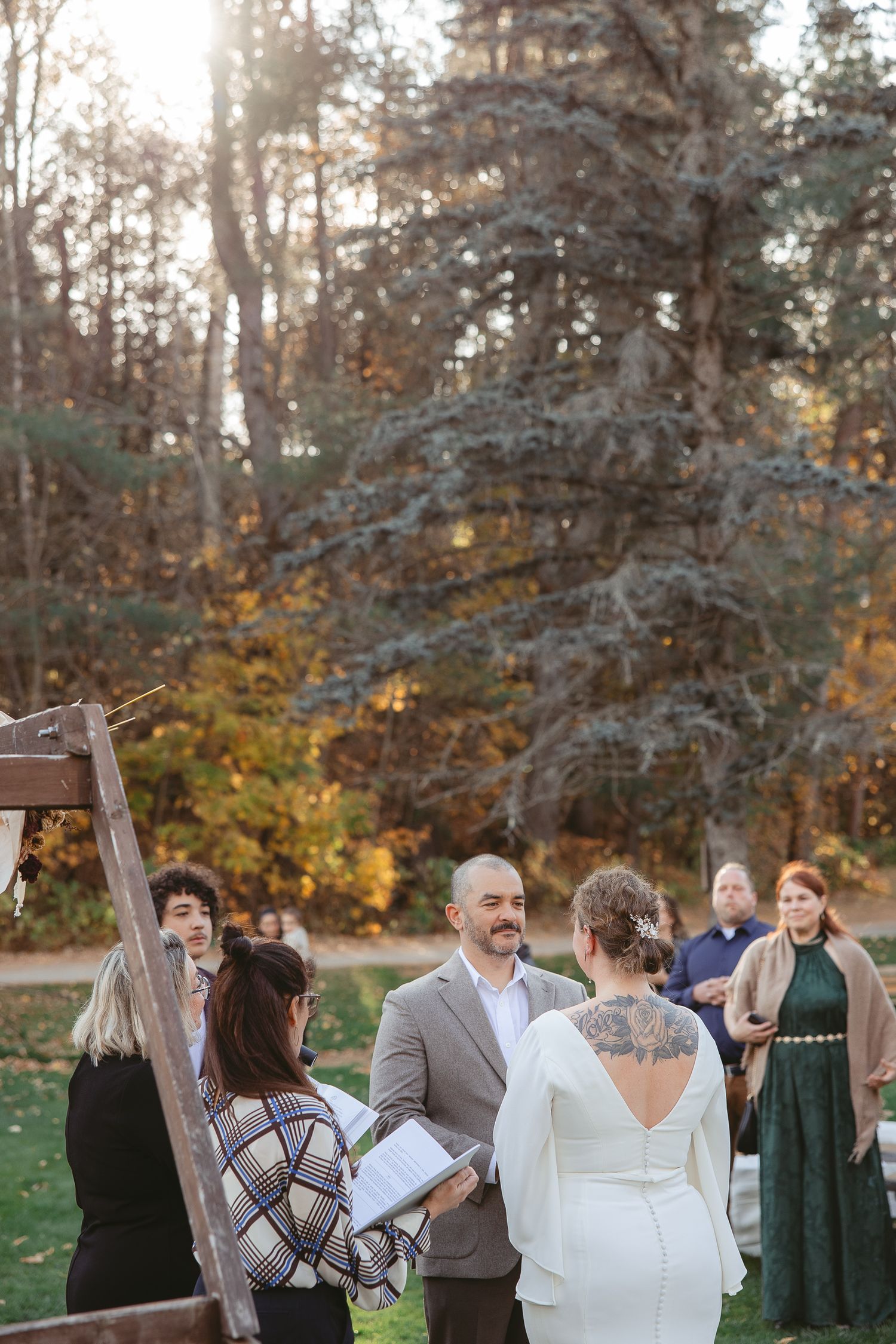 Cérémonie de mariage en plein air au cœur d’une forêt automnale, baignée d’une lumière dorée filtrant à travers les arbres.