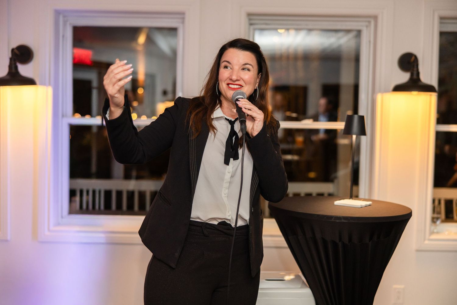 A person in formal attire gestures while speaking during what appears to be a business presentation or conference.