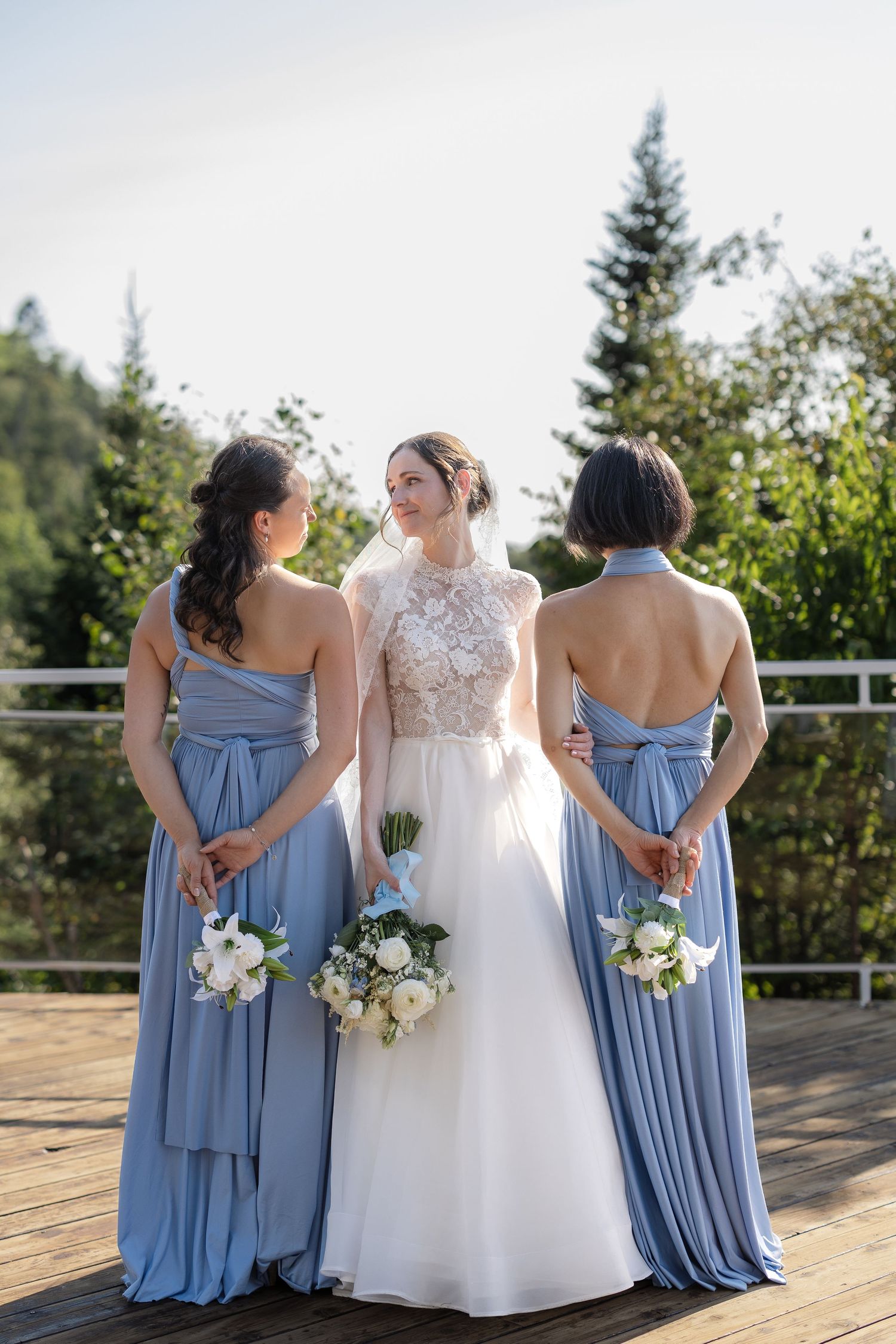 Photo de mariage des demoiselles d’honneur en robes bleues aux côtés de la mariée en robe blanche, en extérieur à l'Auberge de la pointe.