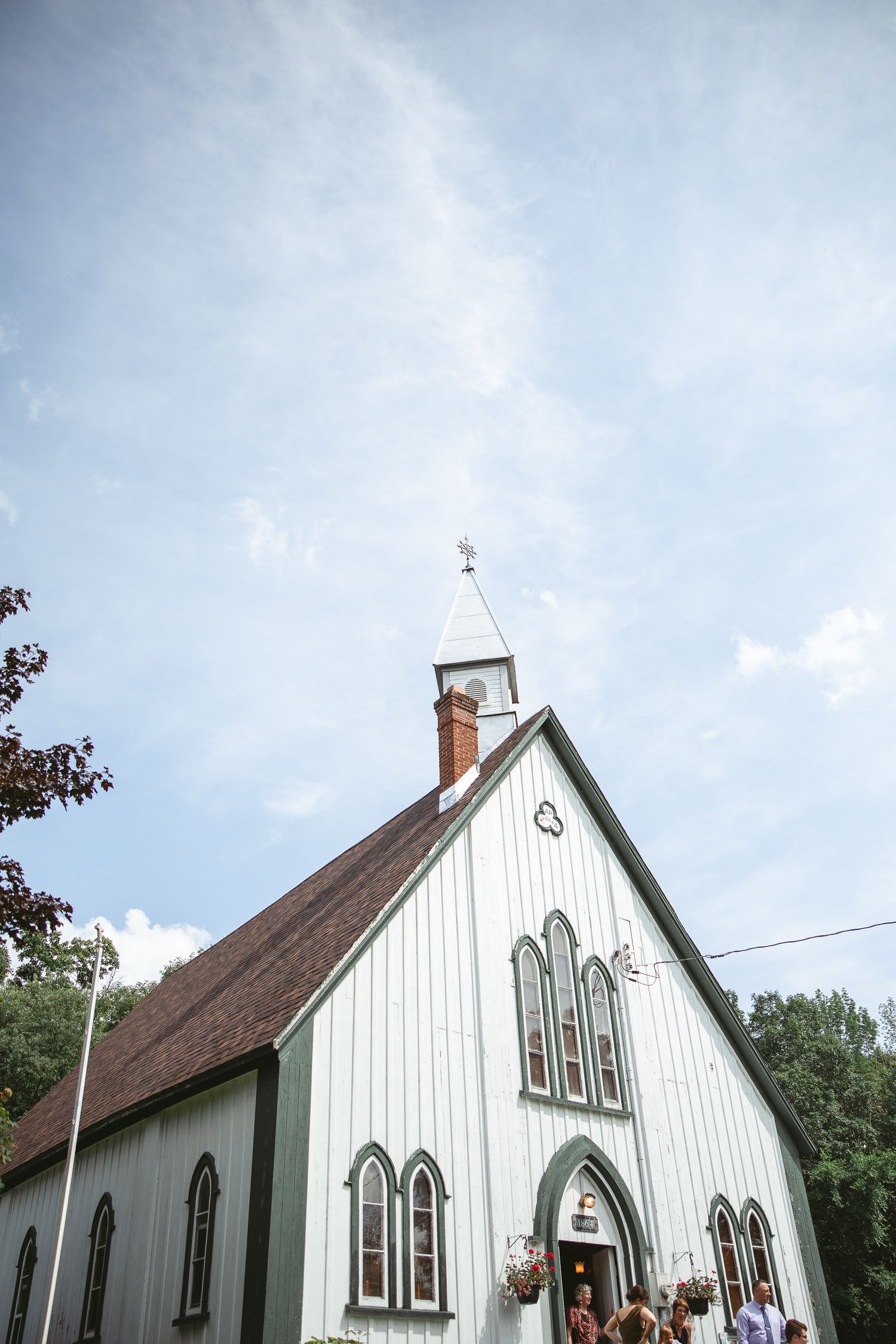 Chapelle blanche en bois au style gothique, avec fenêtres élancées et toit pentu sous un ciel bleu