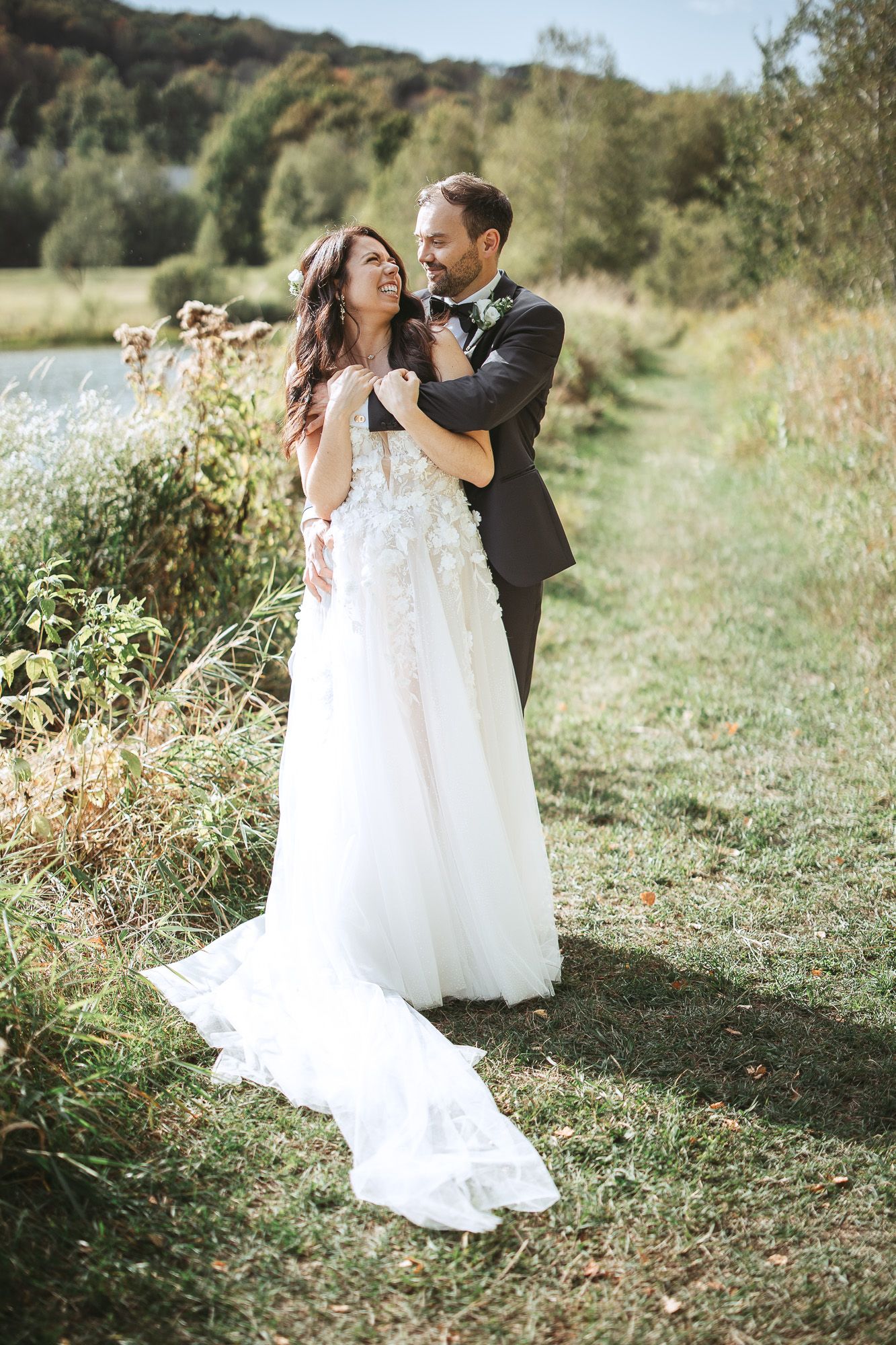 Couple de mariés dansant ensemble dans une prairie ensoleillée, entourée de fleurs sauvages et de nature