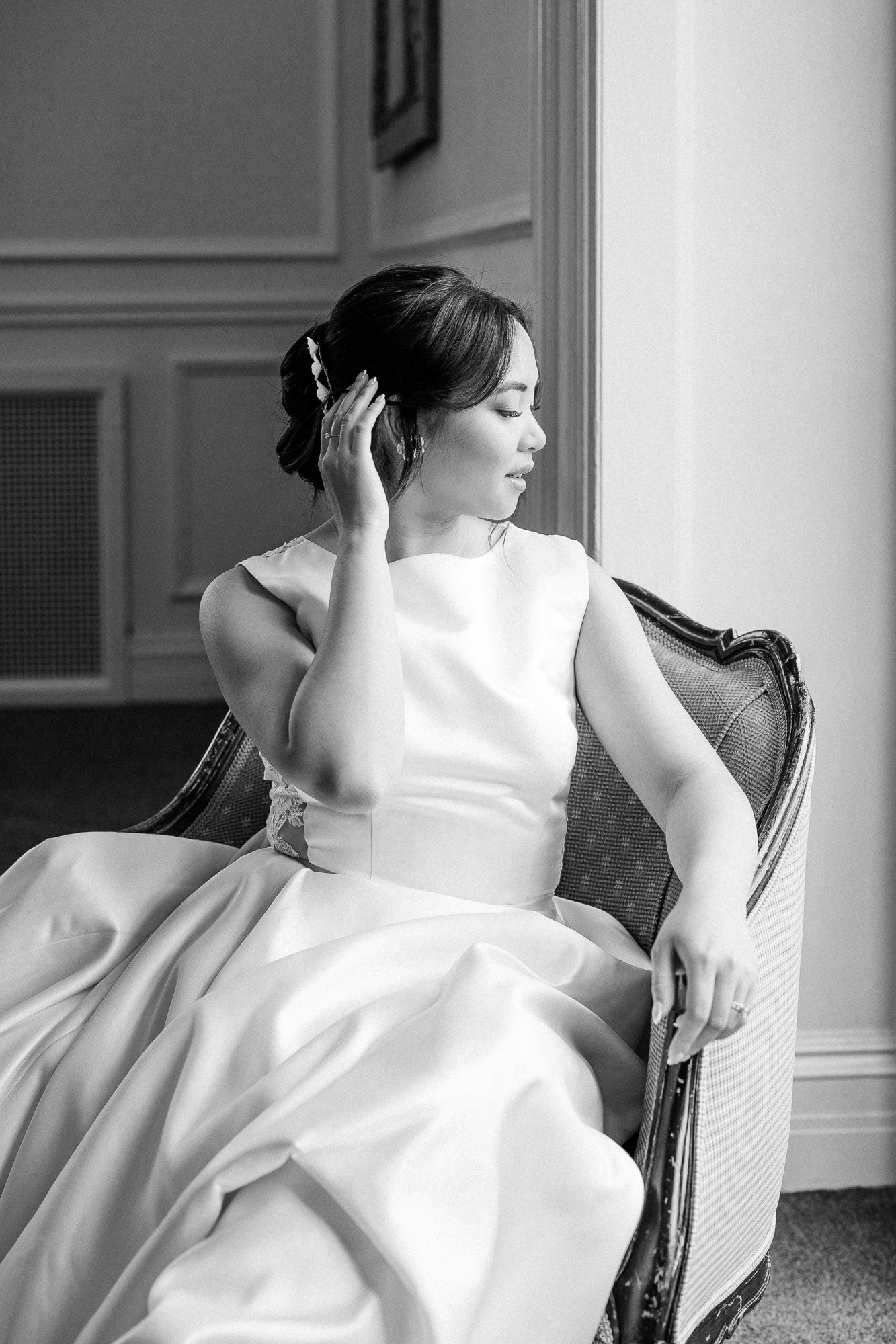 Série artistique en noir et blanc mettant en valeur les détails d’une robe de mariée blanche sur une chaise ancienne