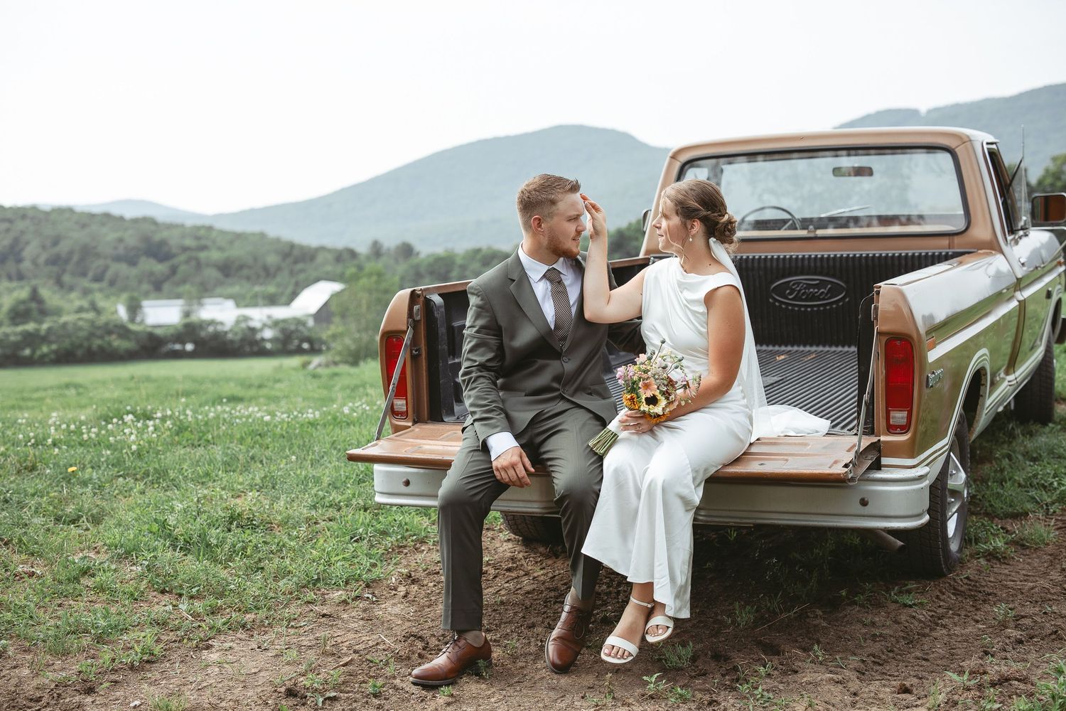 Couple romantique assis sur le hayon d’un pickup Ford vintage dans un champ à la campagne