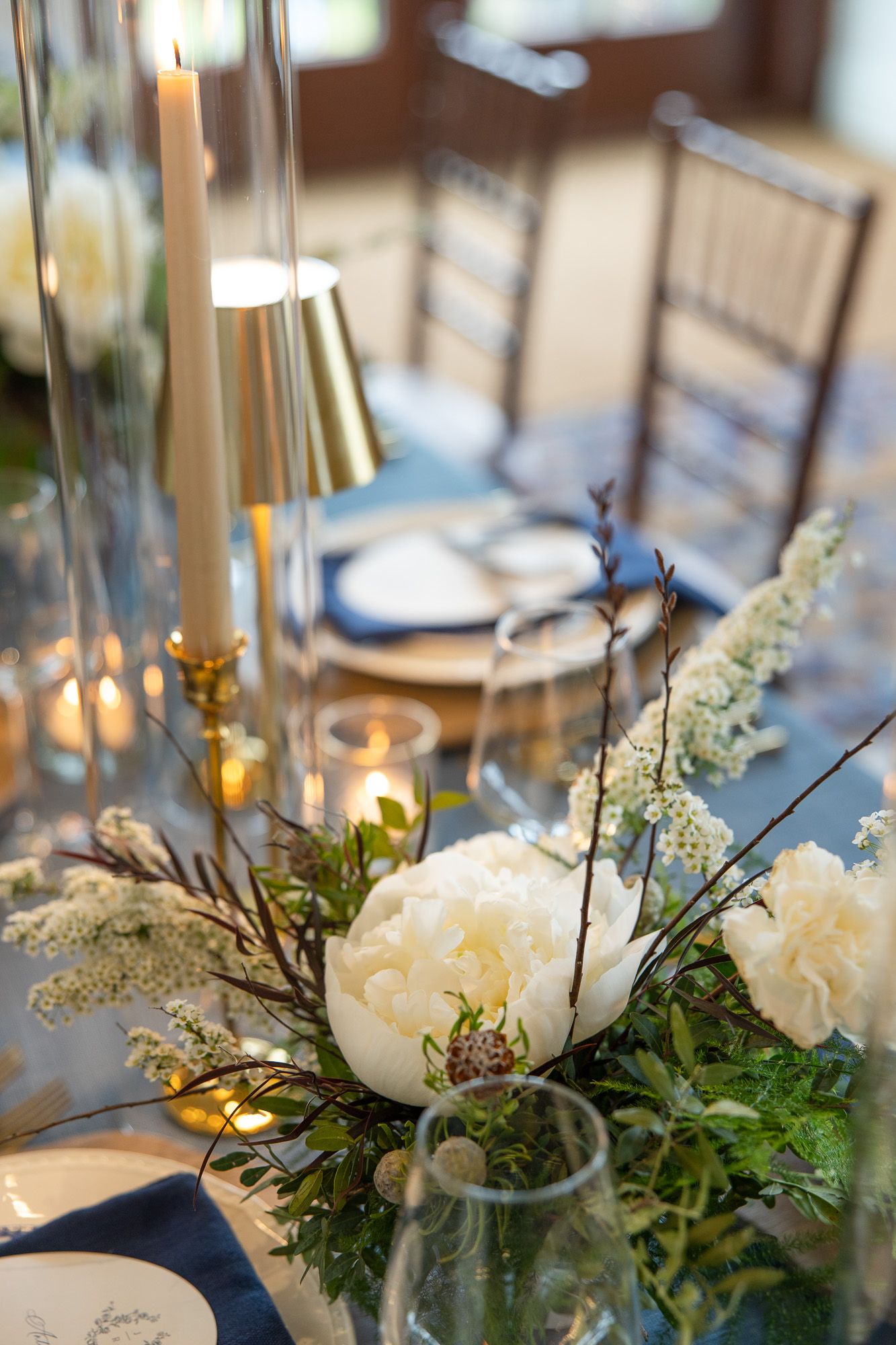 Centre de table floral blanc avec bougies et verdure sur une table de réception élégante