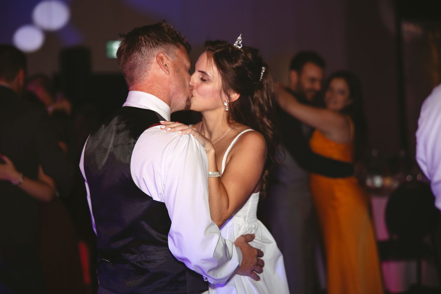 A romantic first dance moment between newlyweds on a dimly lit dance floor at their wedding reception.