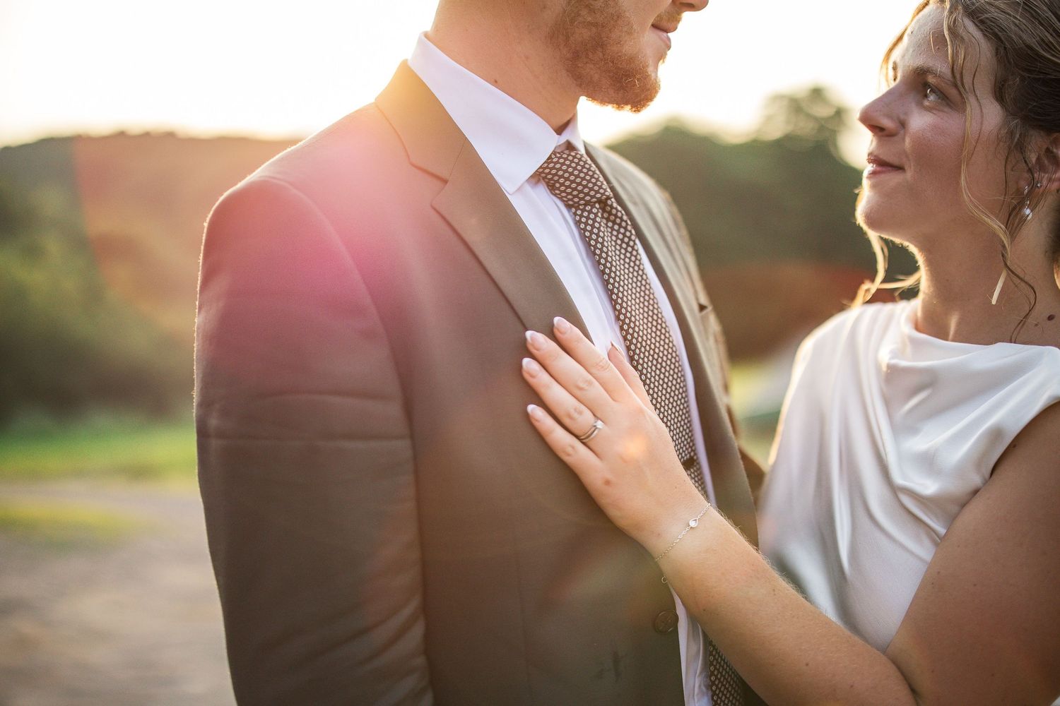 Couple partageant un moment intime lors d’une séance photo de mariage au coucher du soleil sur une ferme