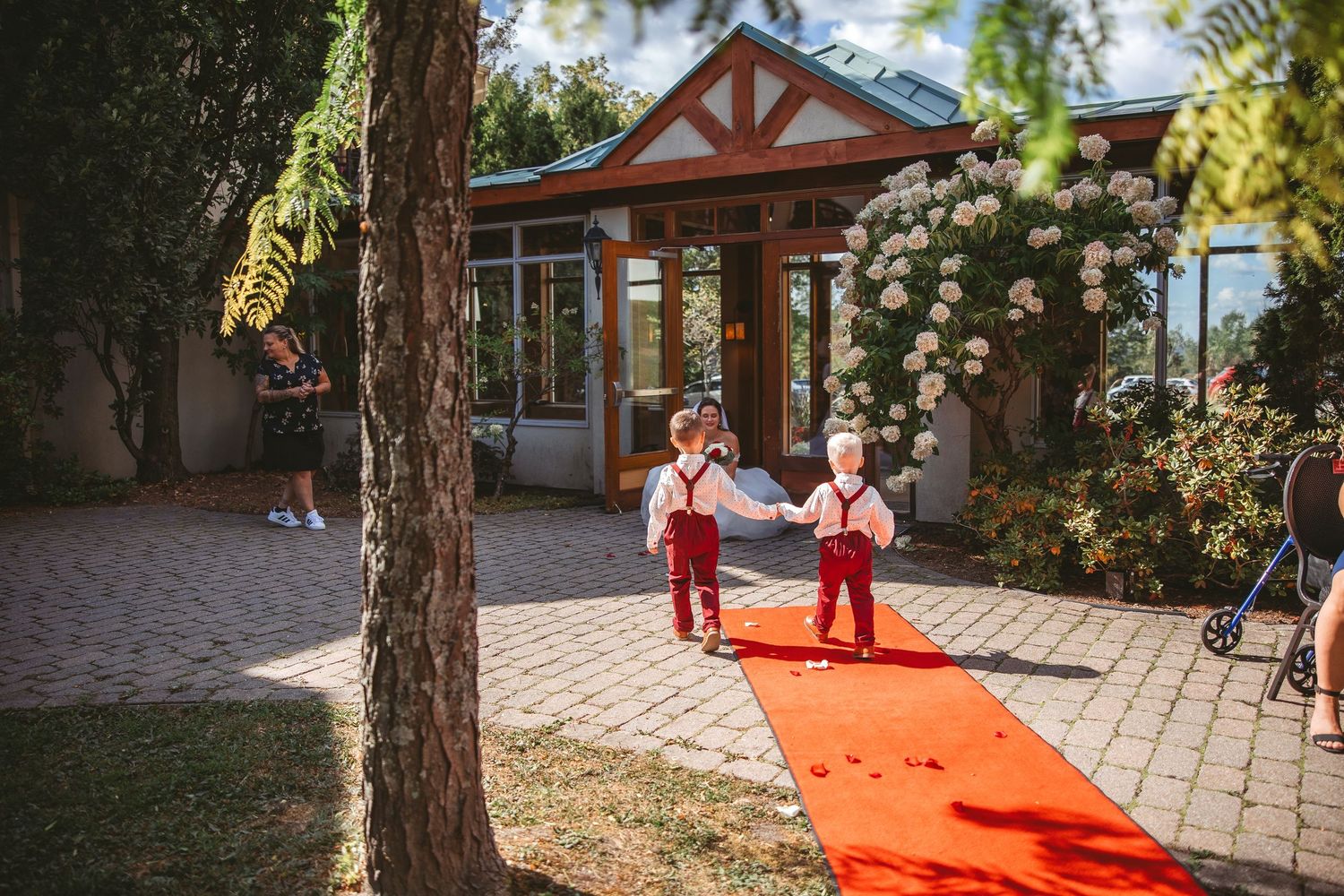 Long red carpet runner extends down outdoor pathway surrounded by trees and buildings.