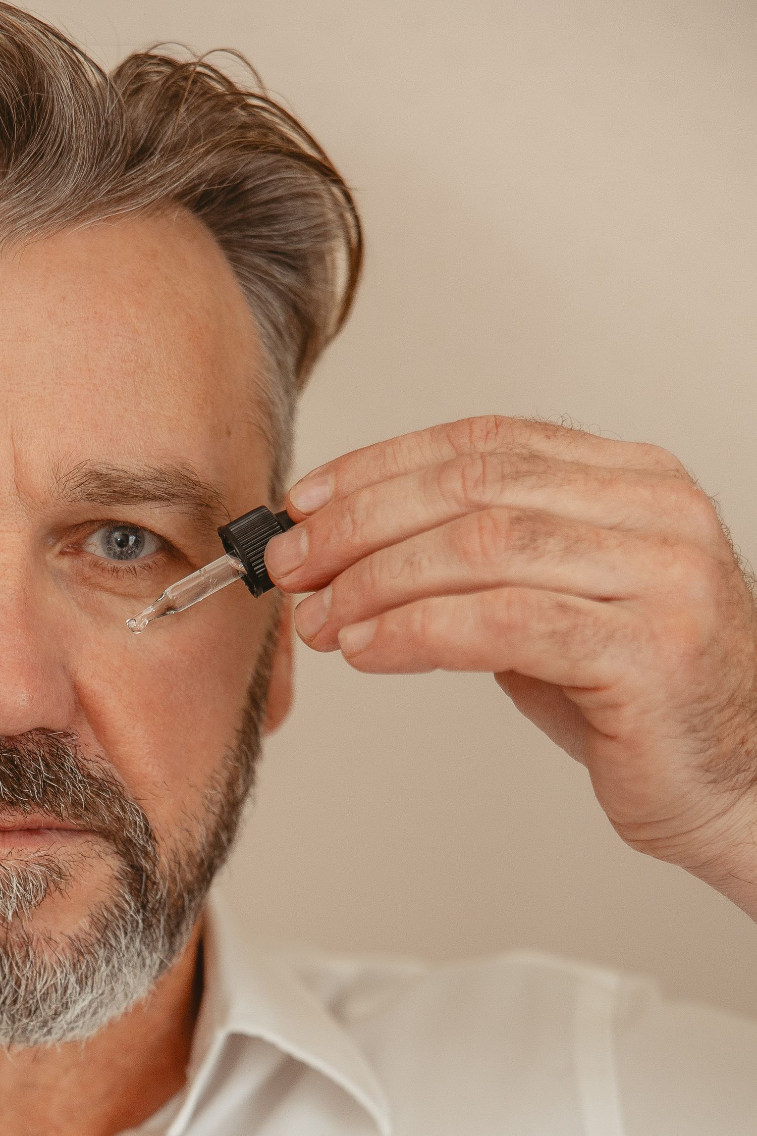 Close-up of hands applying skincare product near eyes.