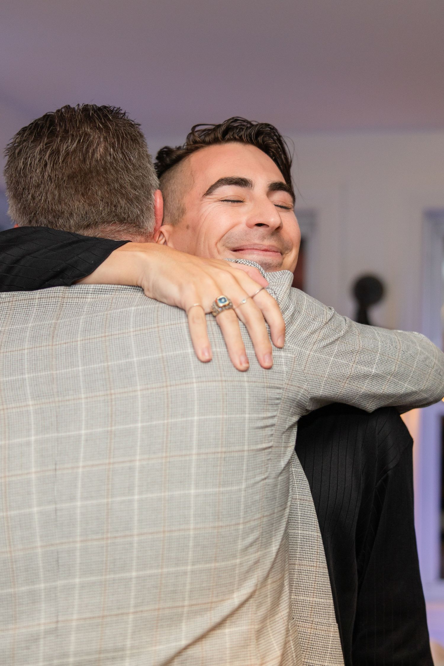 Two people share an emotional embrace at what appears to be a formal event.