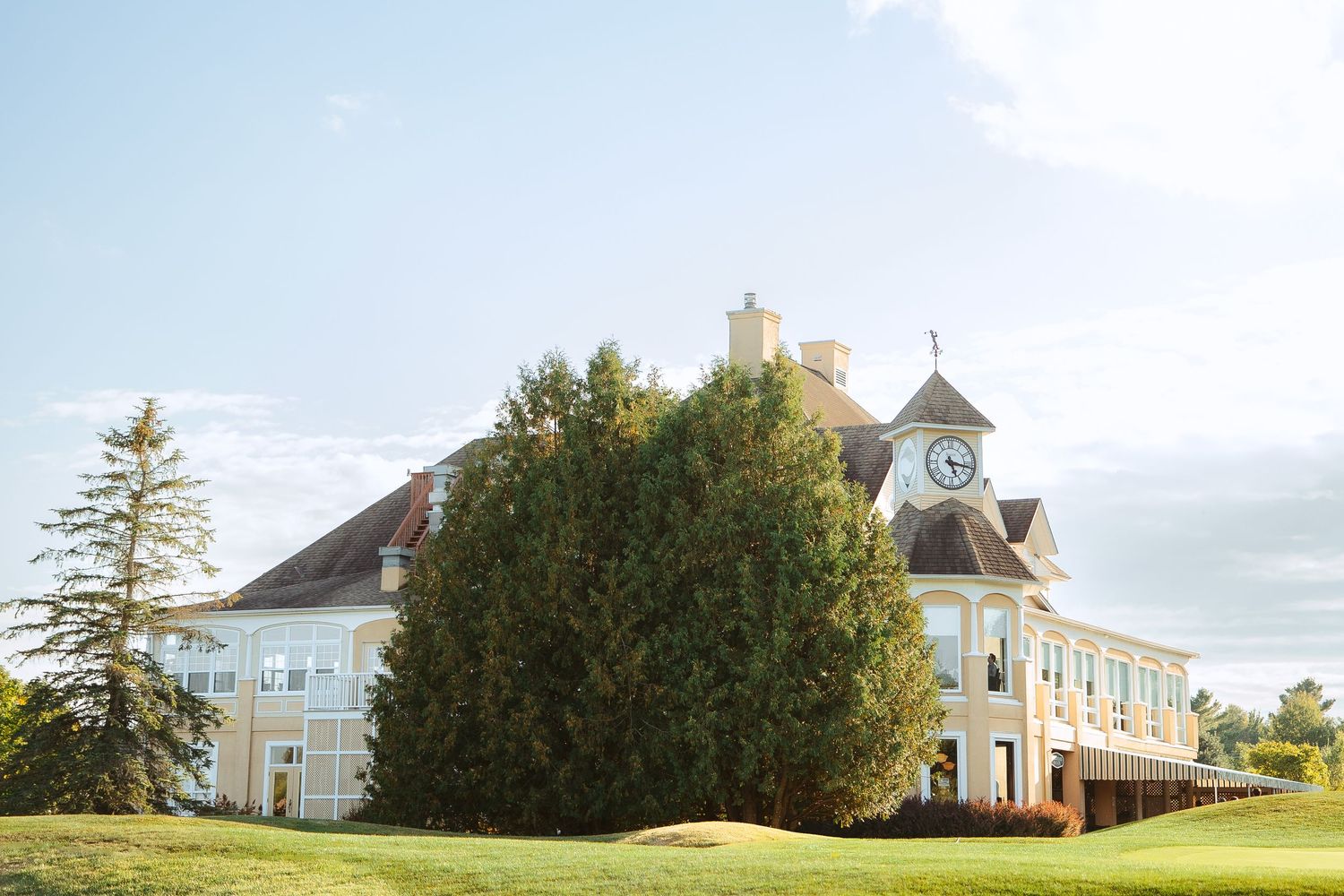 A series of historic lighthouse buildings on a coastal landscape with trees and cloudy skies.
