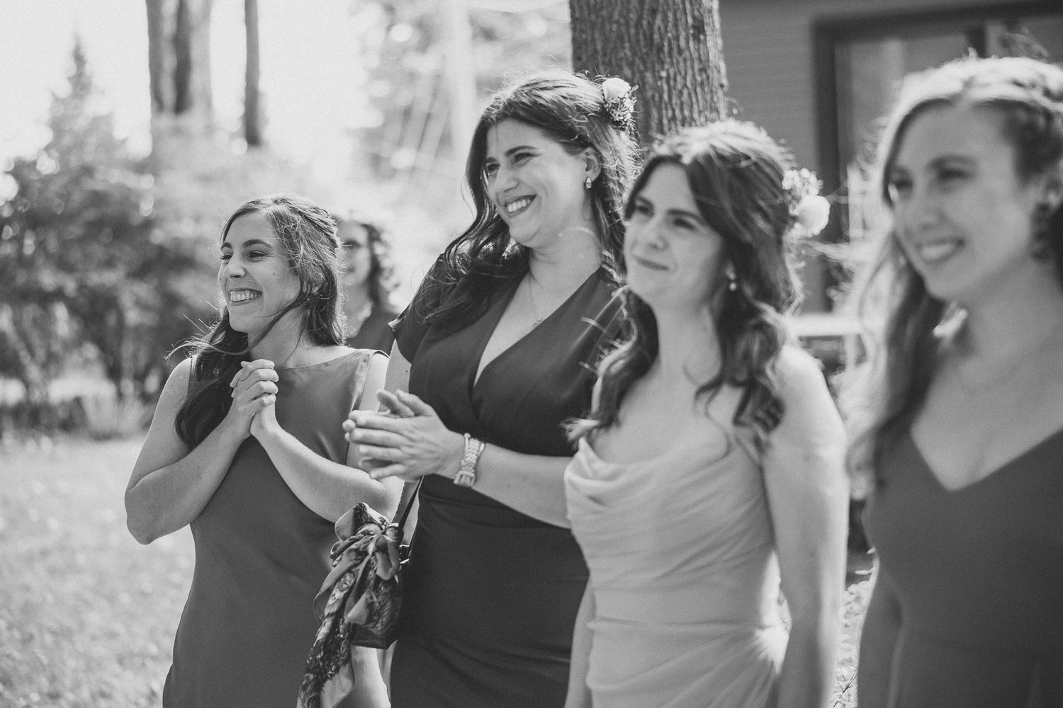 Groupe de demoiselles d’honneur en robes noires et blanches partageant des réactions joyeuses lors d’un mariage en extérieur, en Estrie