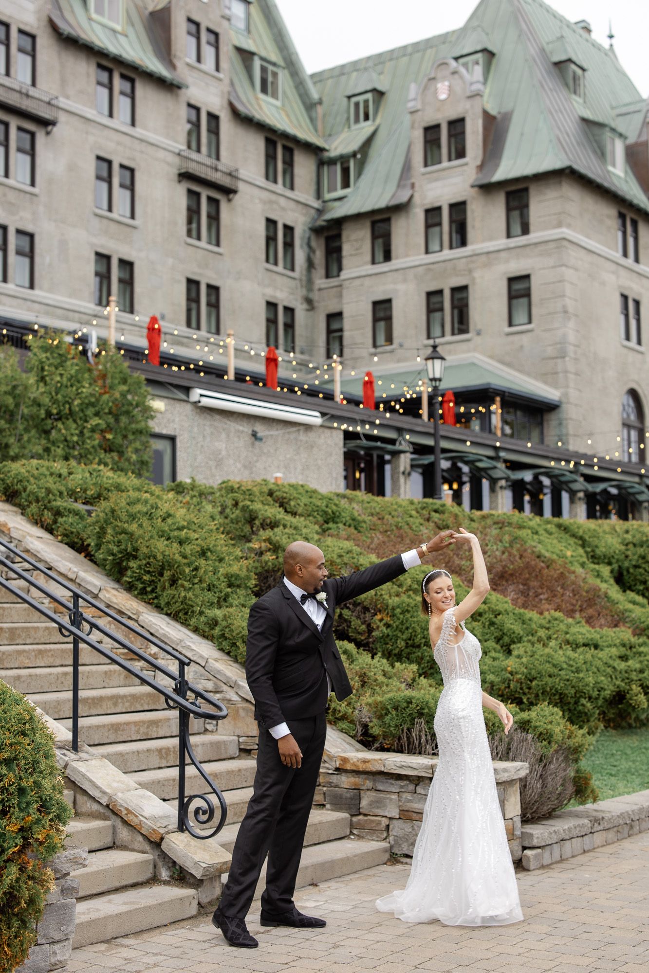 A couple celebrates their wedding day outside a grand historic hotel with stone architecture and copper roofing.