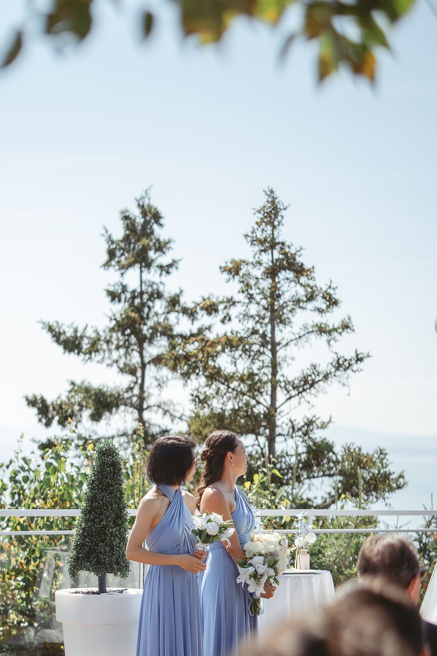 Demoiselles d’honneur en robes bleu pervenche fluides réunies lors d’une cérémonie de mariage en plein air, entourées d’arbres.