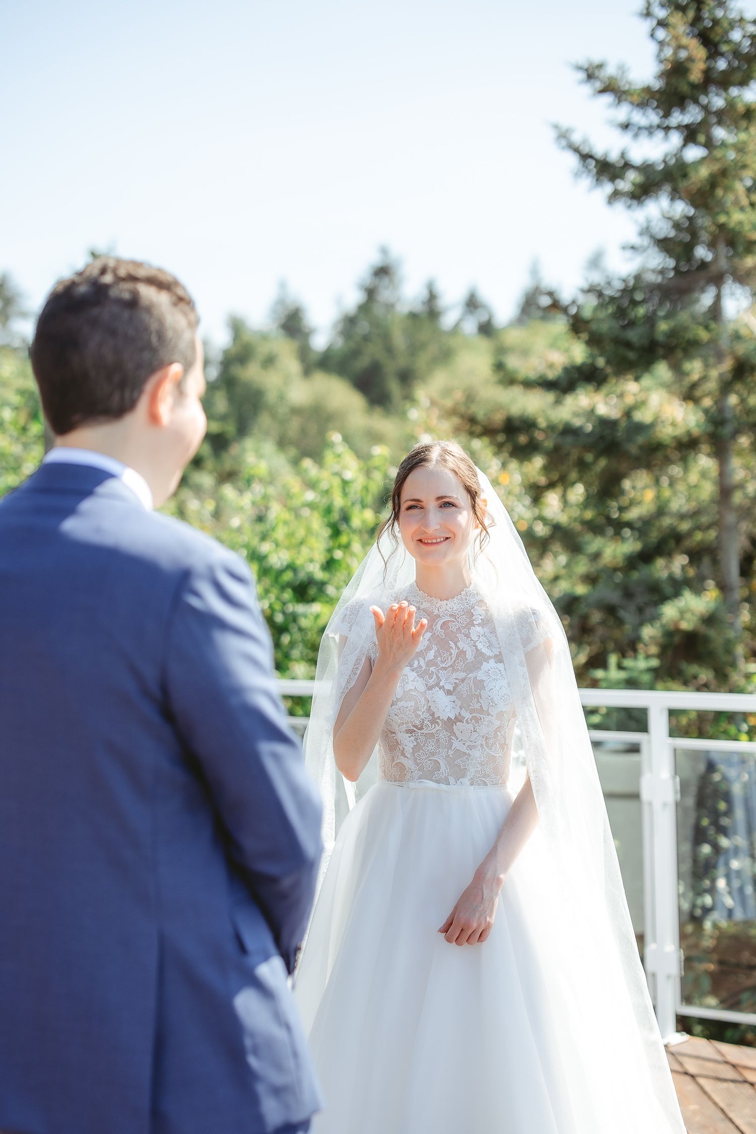 Mariée qui envoi un bec soufflé lors de la cérémonie de son mariage avec des sapins en arrière-plan