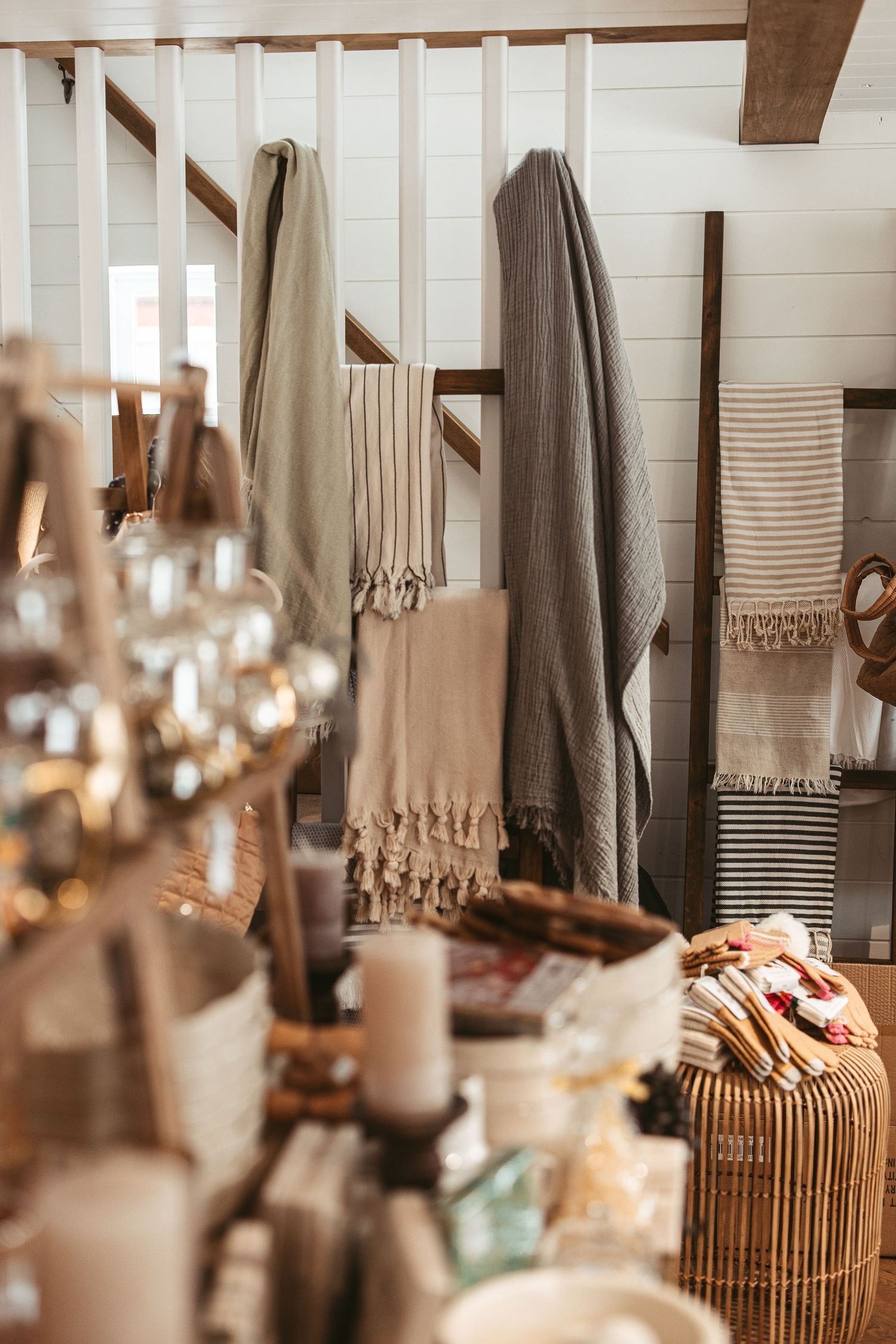 Boutique display of neutral colored textiles and home decor items on wooden shelving.