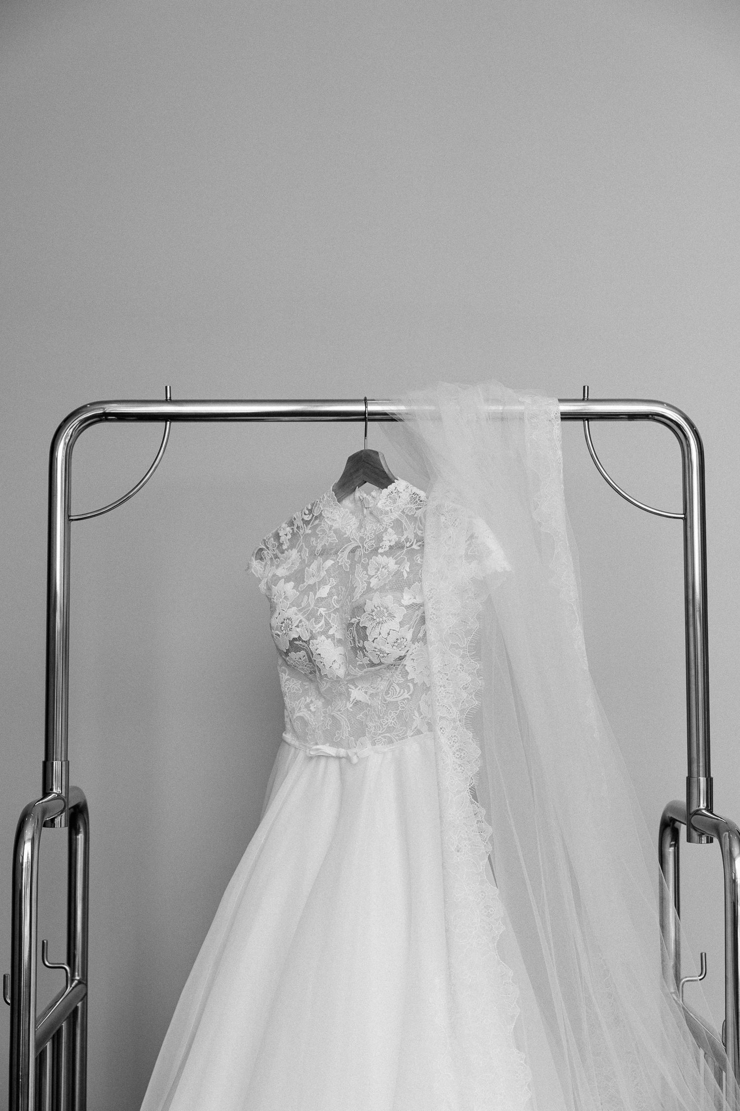 Robe de mariée blanche aux détails de dentelle délicate suspendues sur un porte bagage lors des préparatifs du mariage.
