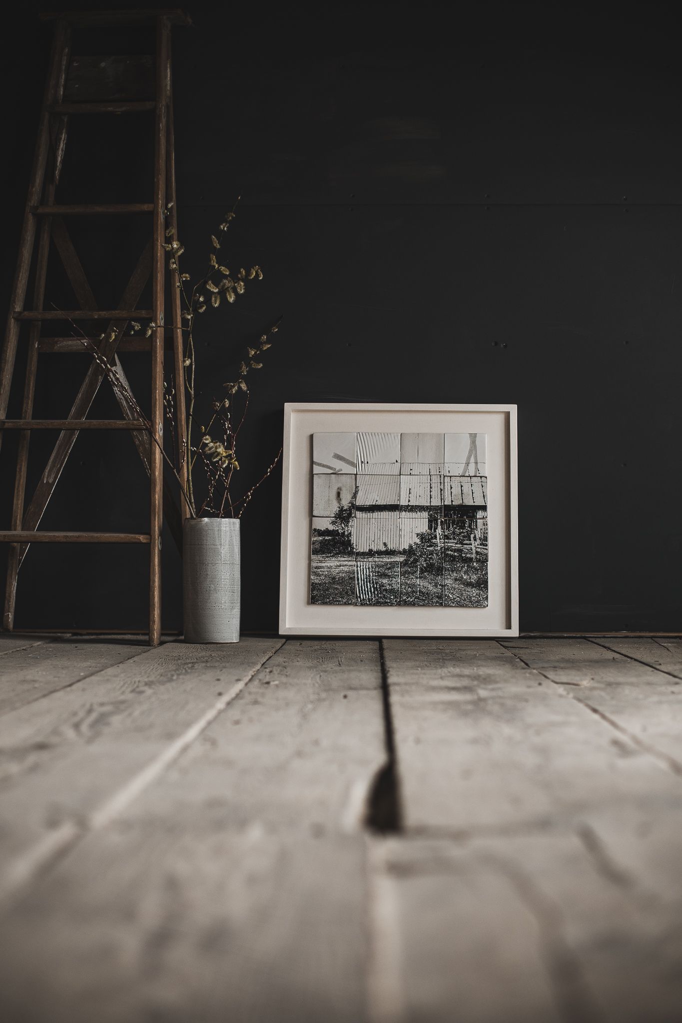 Série de photos minimalistes : échelle en bois, œuvres encadrées et sol en béton, captées dans une lumière douce pour valoriser l’espace