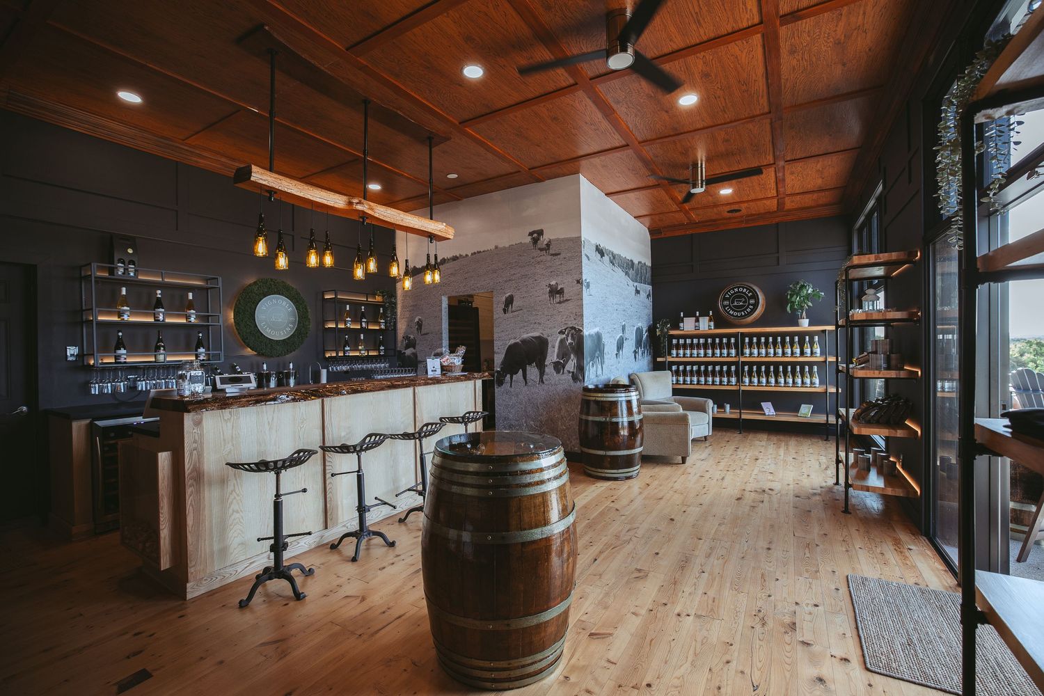 Modern rustic tasting room interior with wood barrel decor, exposed beams, and pendant lighting creates warm ambiance.