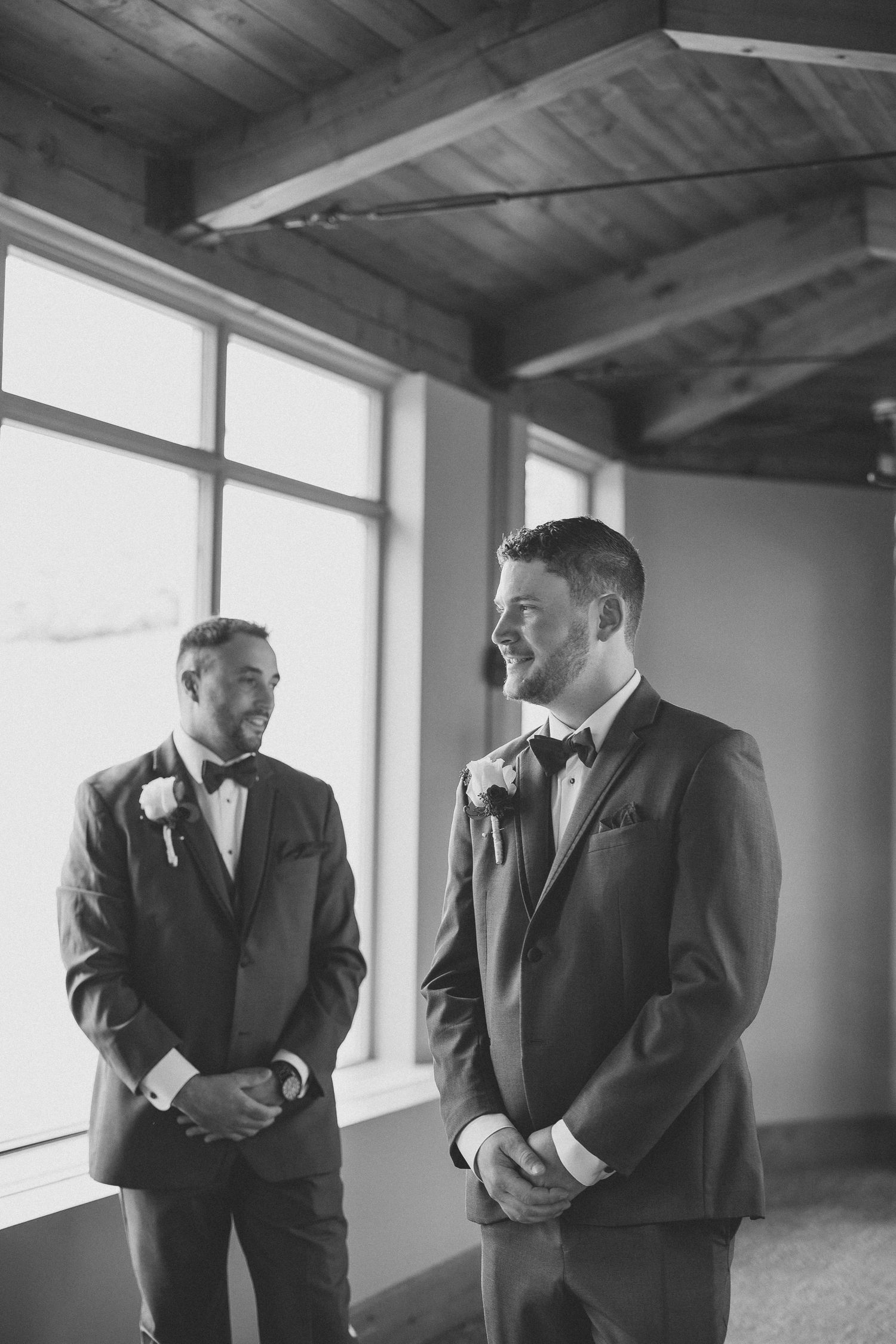 Black and white photo series showing two men in suits having an animated conversation near large windows.