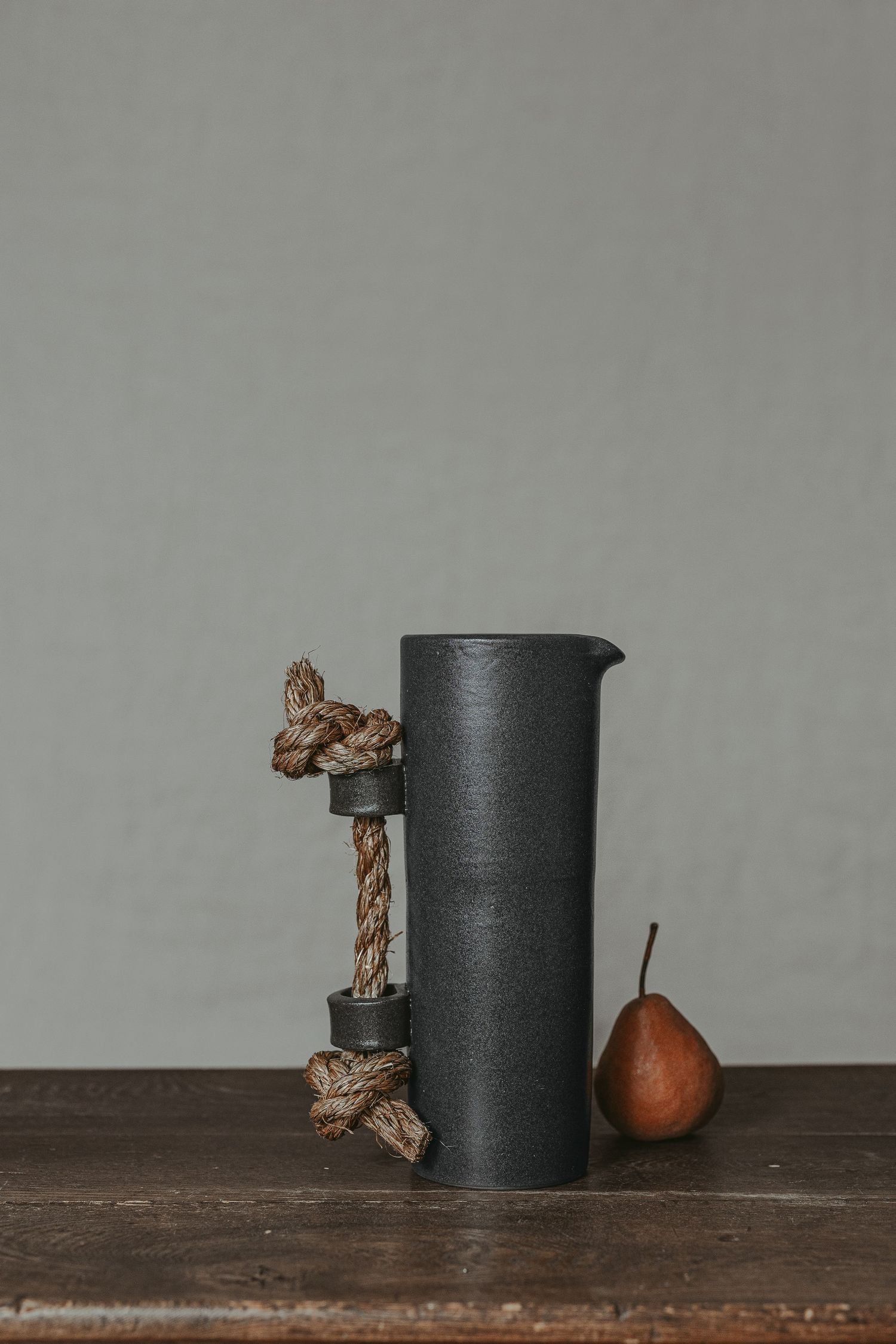 Photographie de produit : pot de fleur noir avec botanique séchée et poire, posé sur bois sombre pour mettre en valeur textures et design