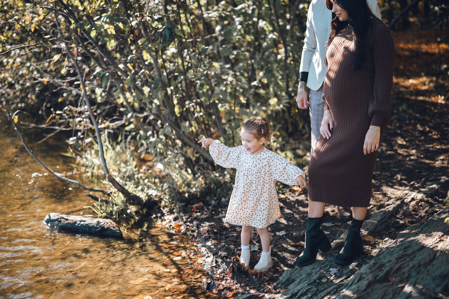 Family portrait session among autumn trees and fallen leaves.