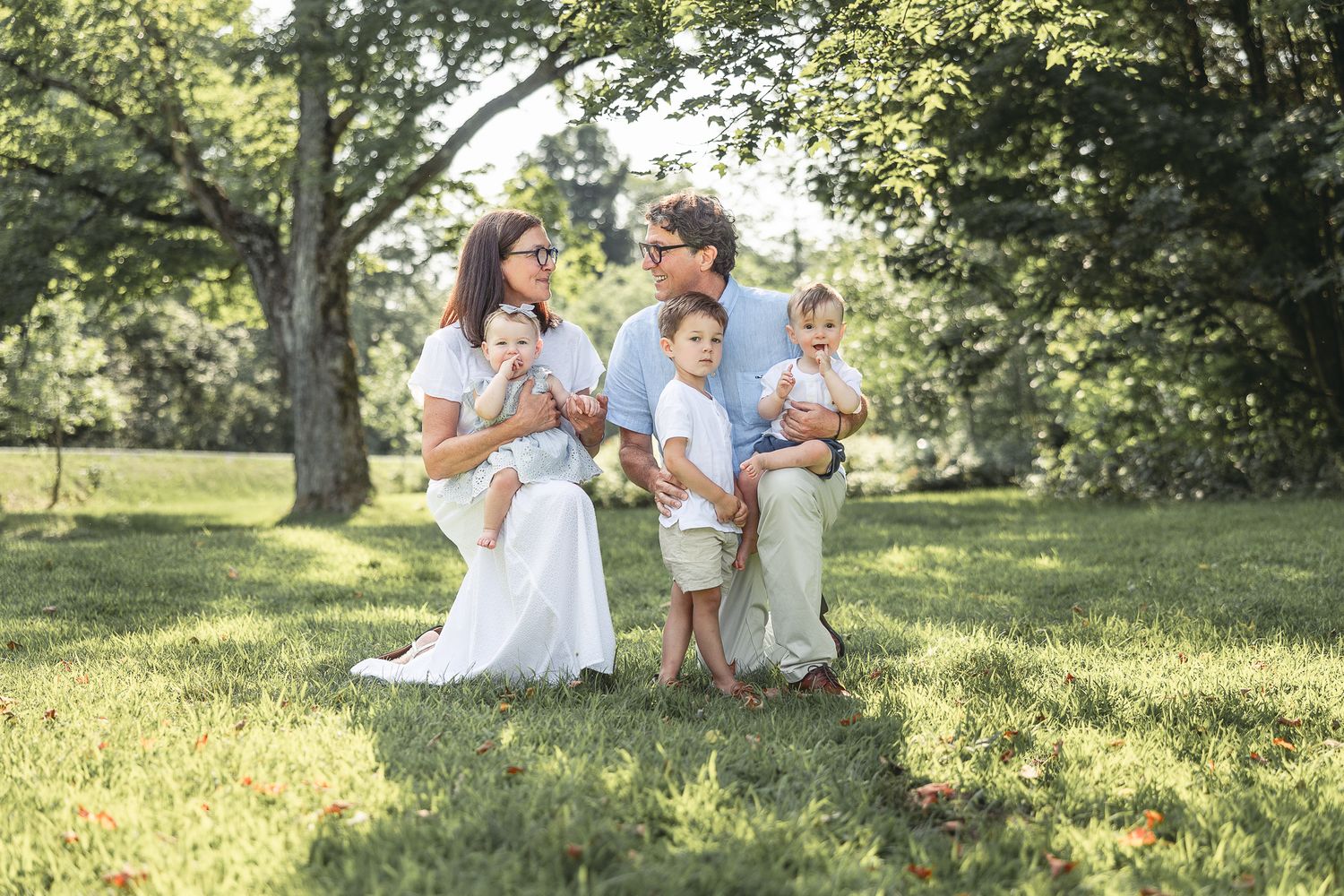 Grands-parents assis avec leurs petits-enfants dans un pré ensoleillé, capturés lors d’une séance photo estivale pour moments tendres