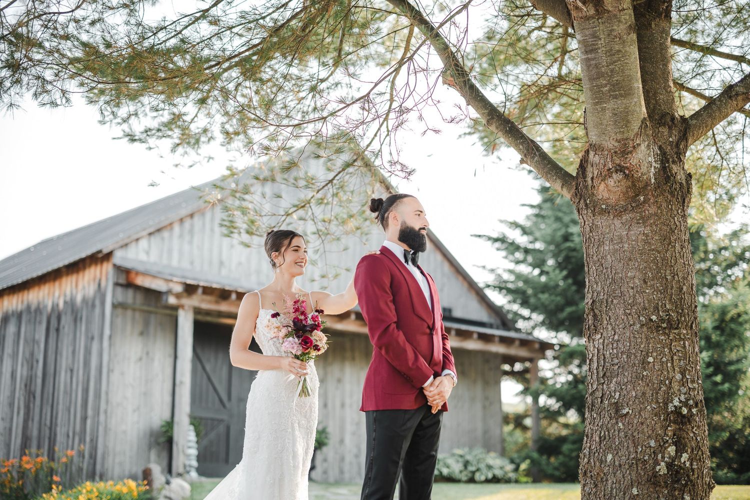 A romantic couple shares tender moments in front of a rustic barn during an outdoor photo session.
