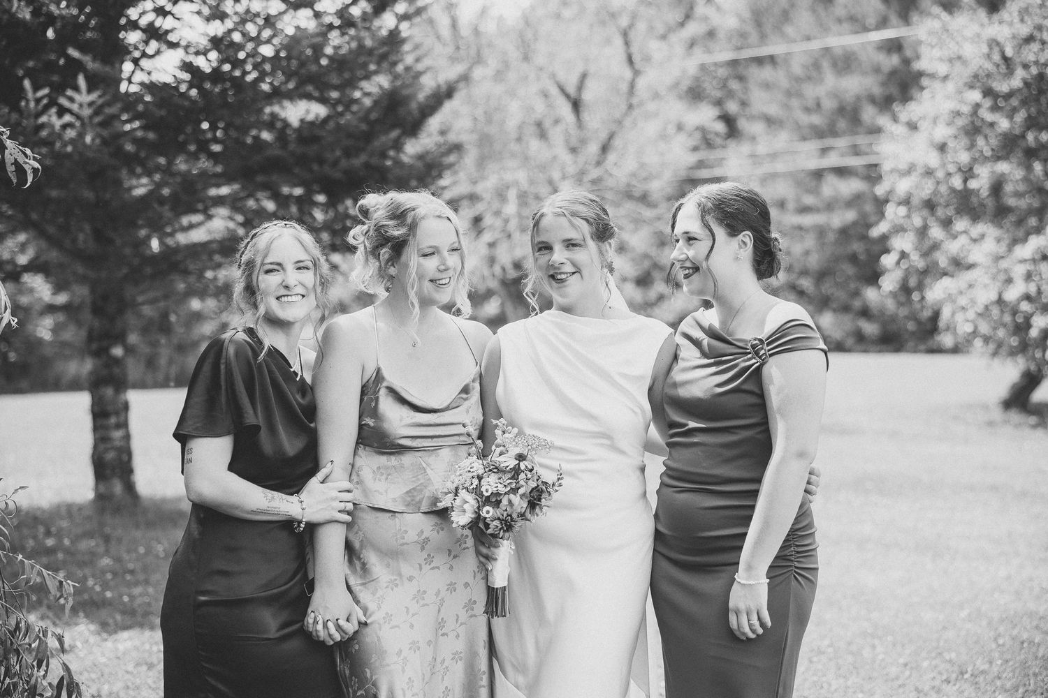filles d'honeur et la mariée marchant ensemble sur un sentier de jardin, photographie en noir et blanc