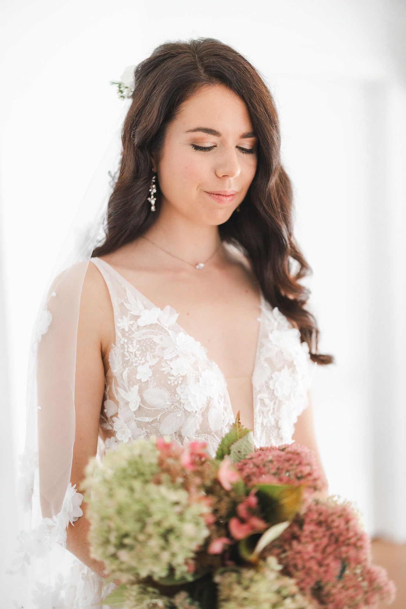 Portrait de mariée élégant mettant en valeur une robe blanche en dentelle et un bouquet floral romantique