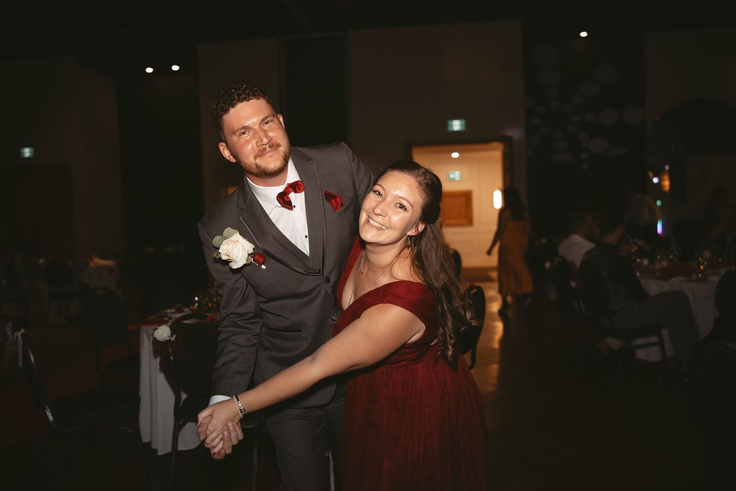 Couples dancing together at a formal event in a dimly lit ballroom.