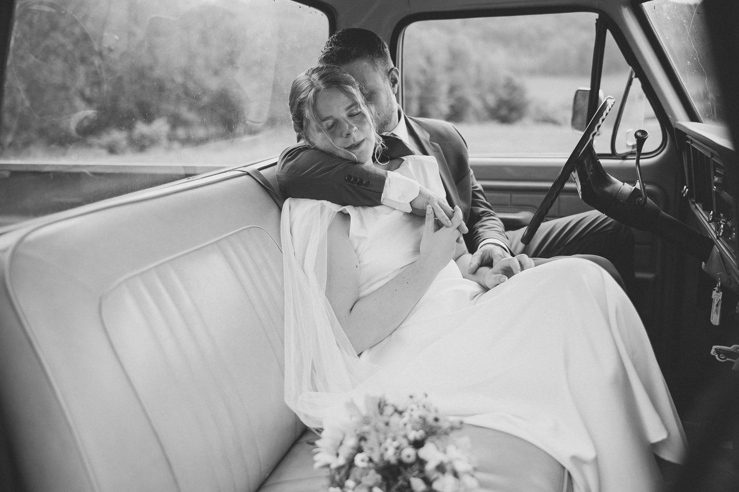 Série romantique en noir et blanc d’un couple dans une voiture vintage lors de leur mariage