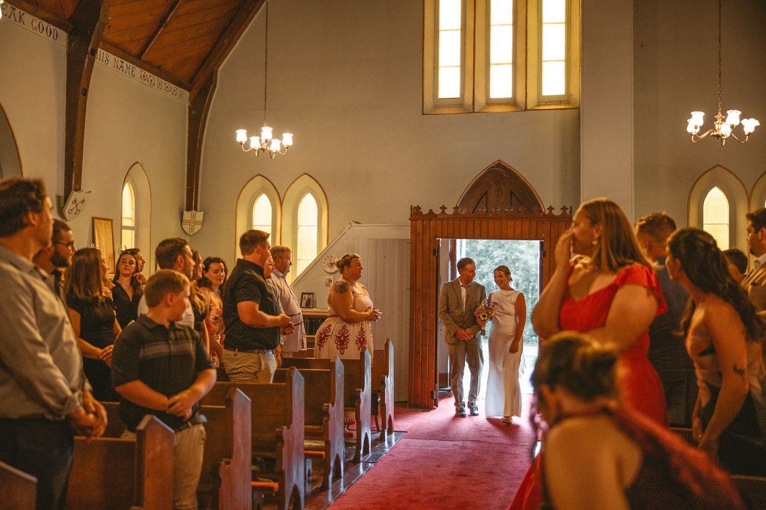 Cérémonie de mariage dans une église traditionnelle avec bancs en bois et éclairage chaleureux de lustres