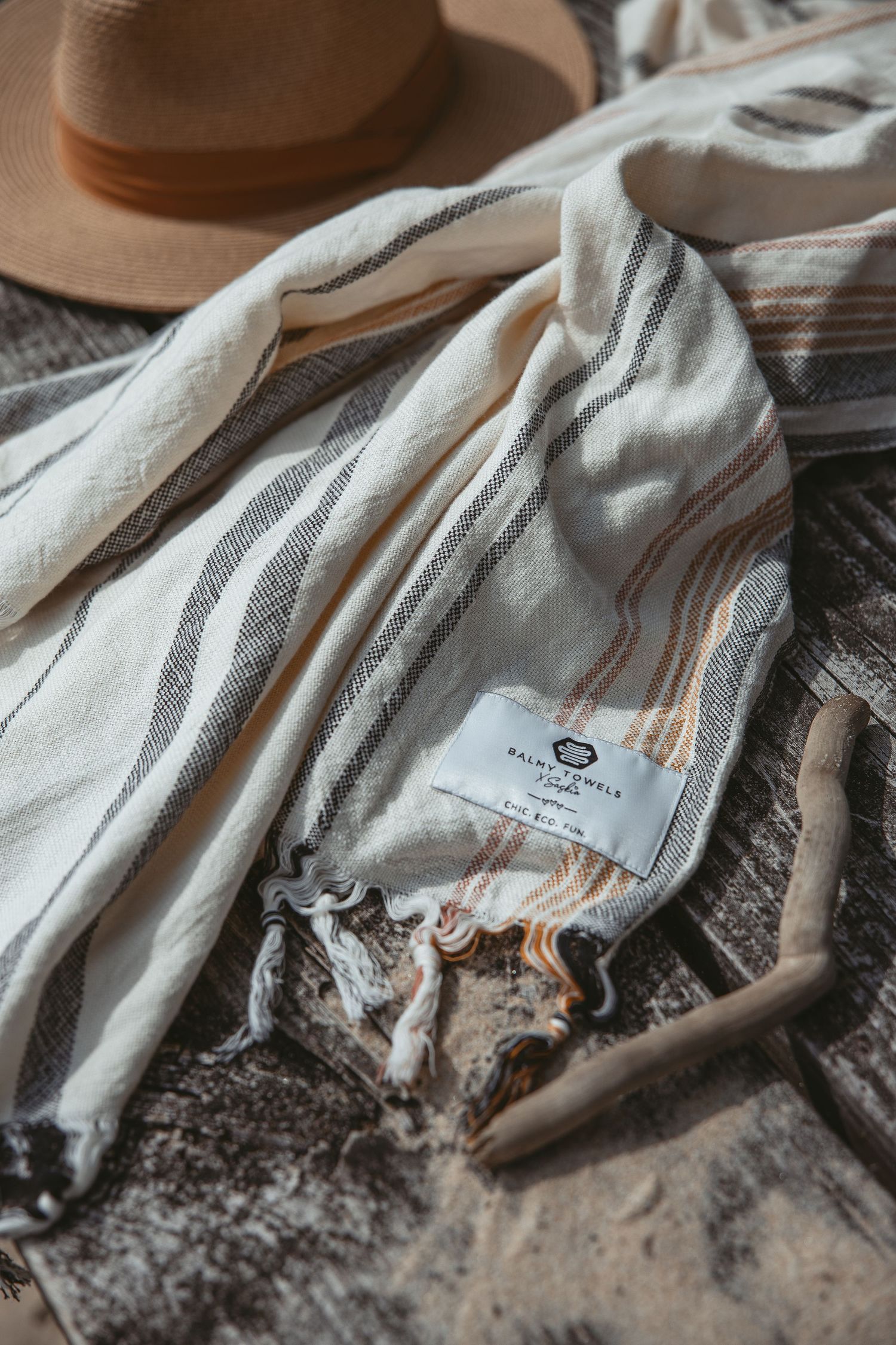 Gray and white striped textile with tassels laid on weathered wood surface.