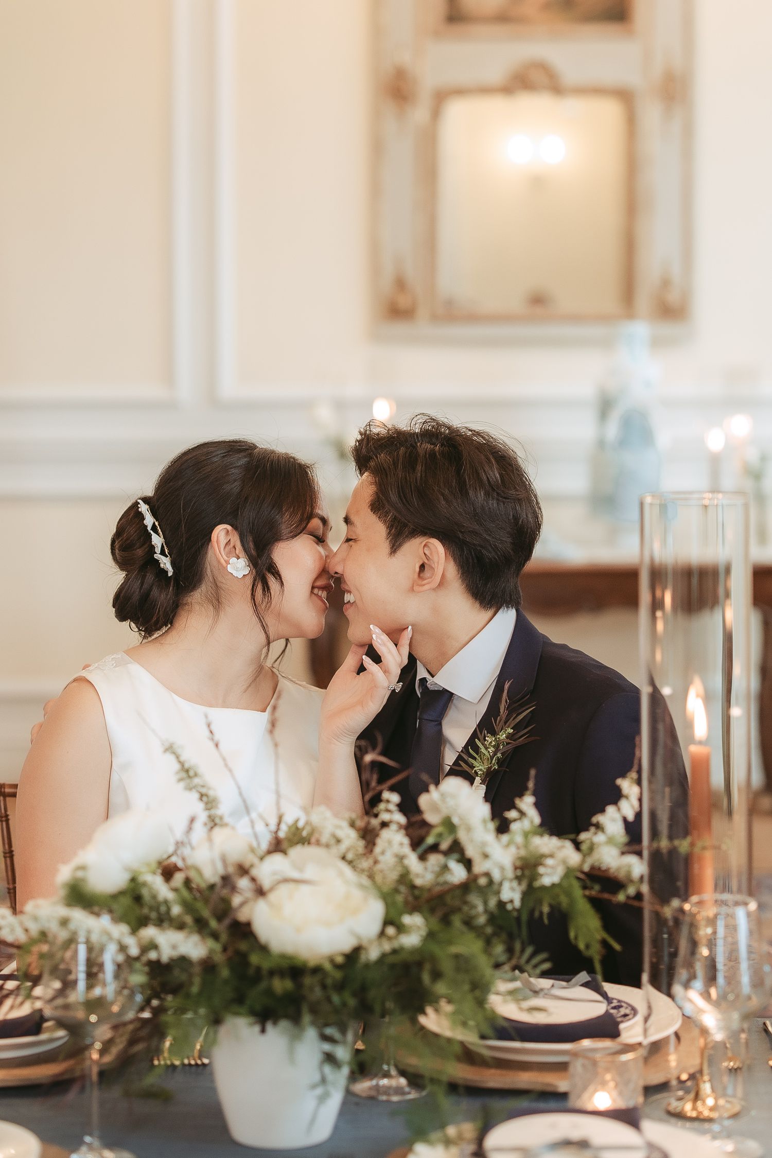 Mariés qui s'embrassent dans un décor de table de mariage romantique, chandelles et vaisselle élégante pour la réception au manoir Richelieu