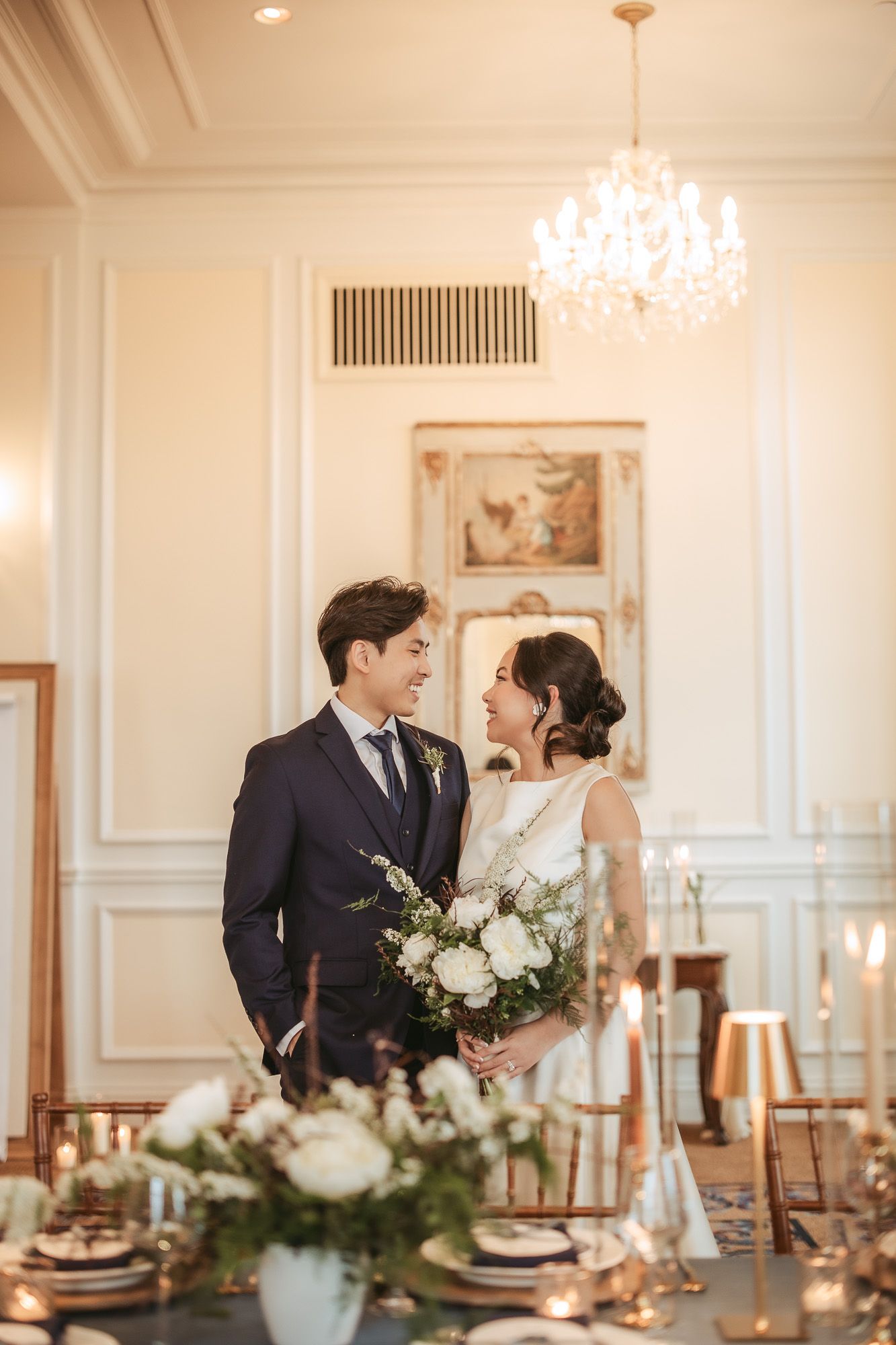 Mise en scène élégante de réception de mariage avec lustre en cristal et centres de table floraux blancs sur table formelle