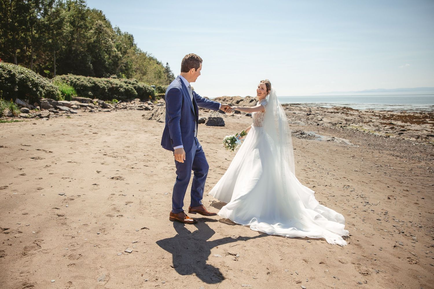 Couple de mariés partageant un moment intime au coucher du soleil, le long d’une plage au décor naturel et romantique.
