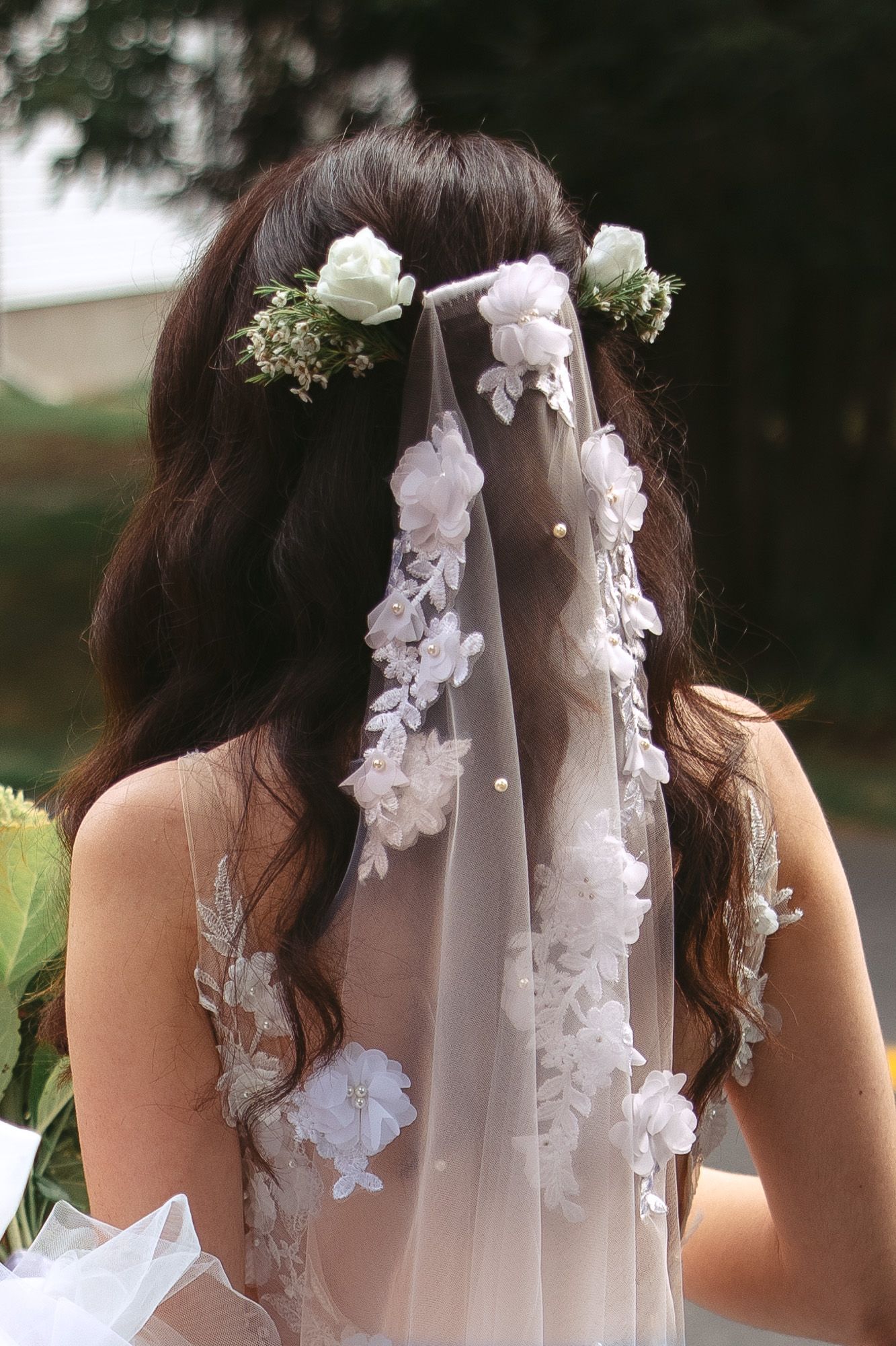 Détails floraux blancs délicats ornant un voile de mariée sur fond sombre
