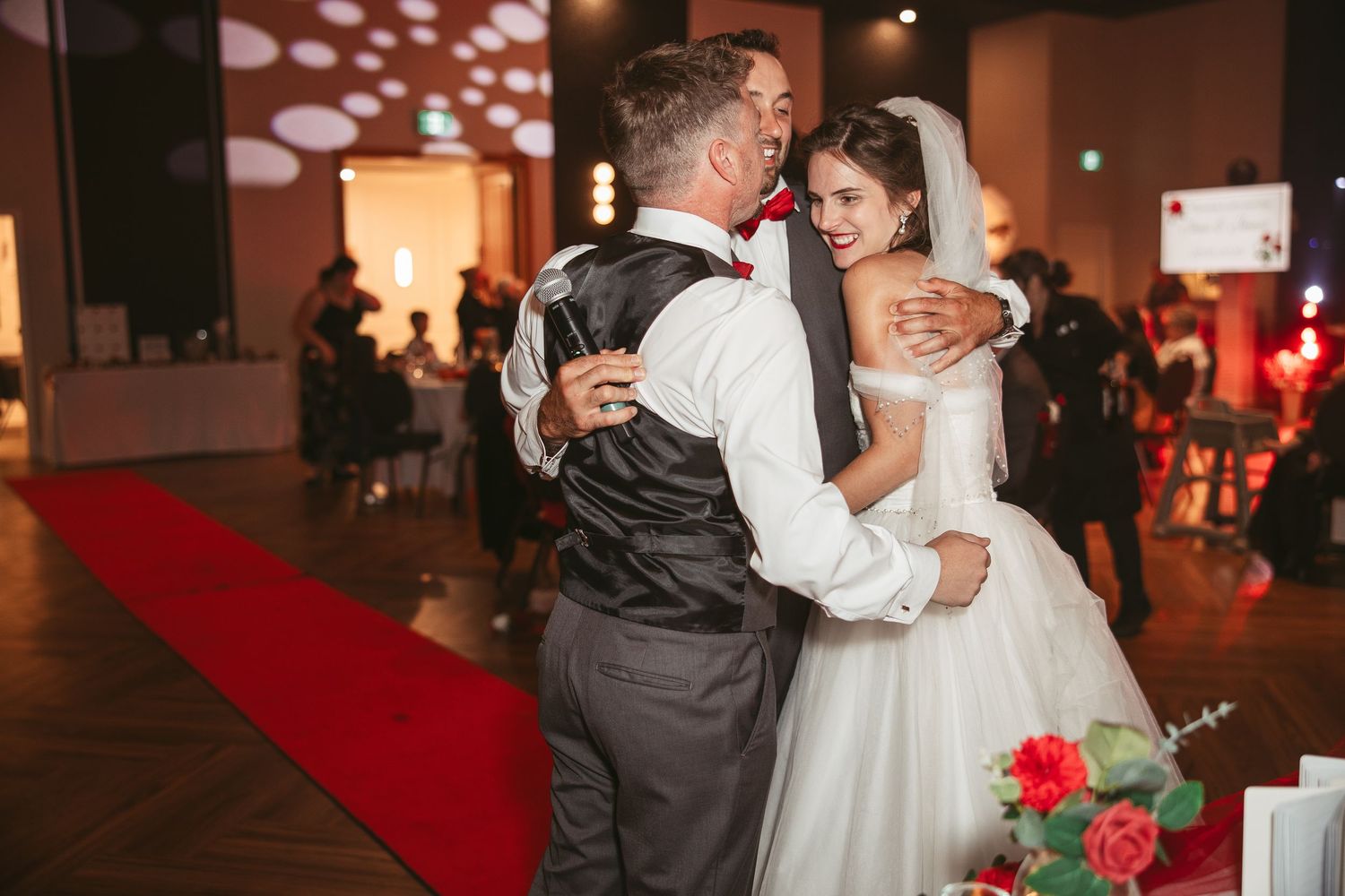 Wedding couple sharing first dance on illuminated red carpet.