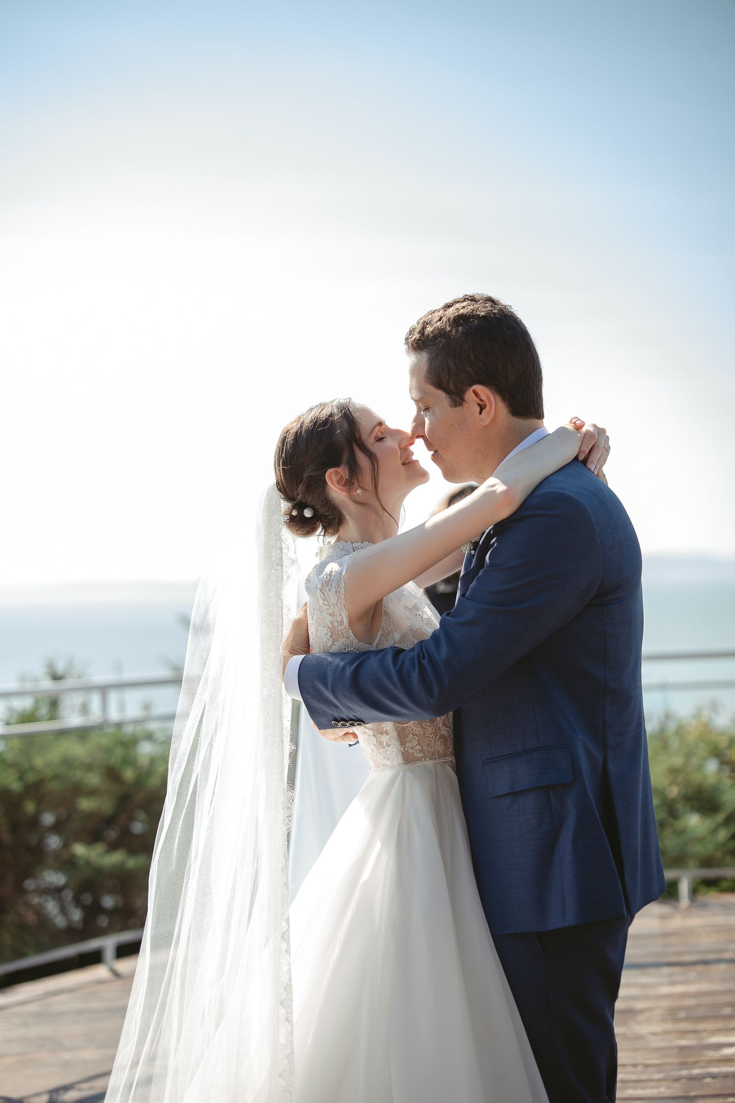 Couple de mariés qui s'embrassent lors de leur cérémonie de mariage en plein air, dans un décor naturel et panoramique.