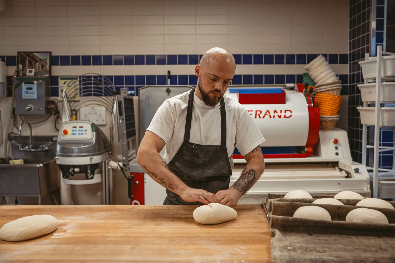 Baker shaping bread dough at professional workstation.